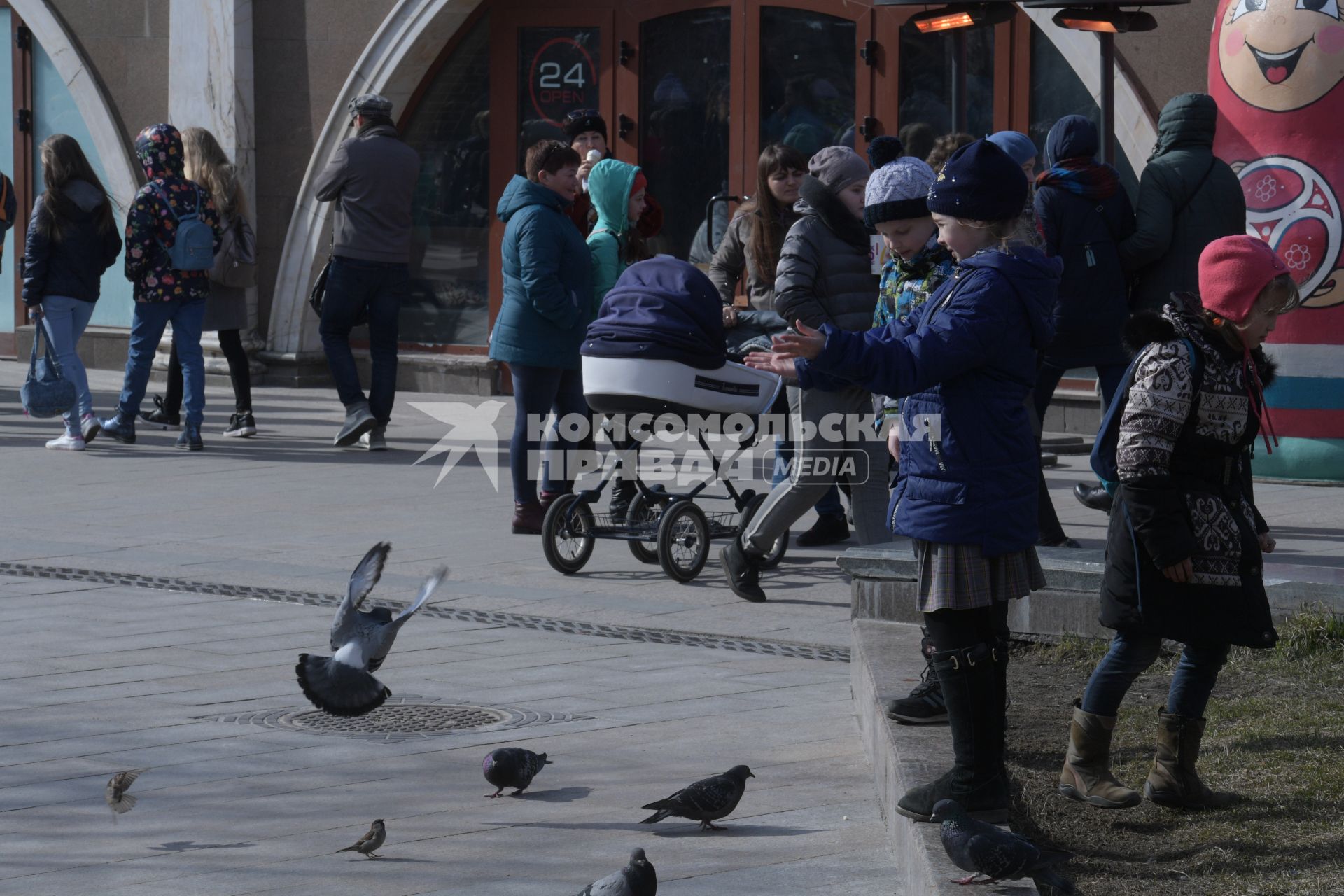 Москва. Девочка кормит голубей на Манежной площади.