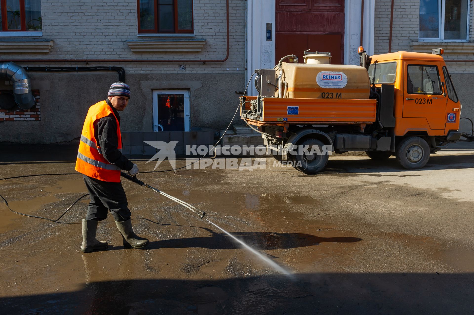 Санкт-Петербург. Сотрудник  ЖКХ  моет дорогу во дворе.