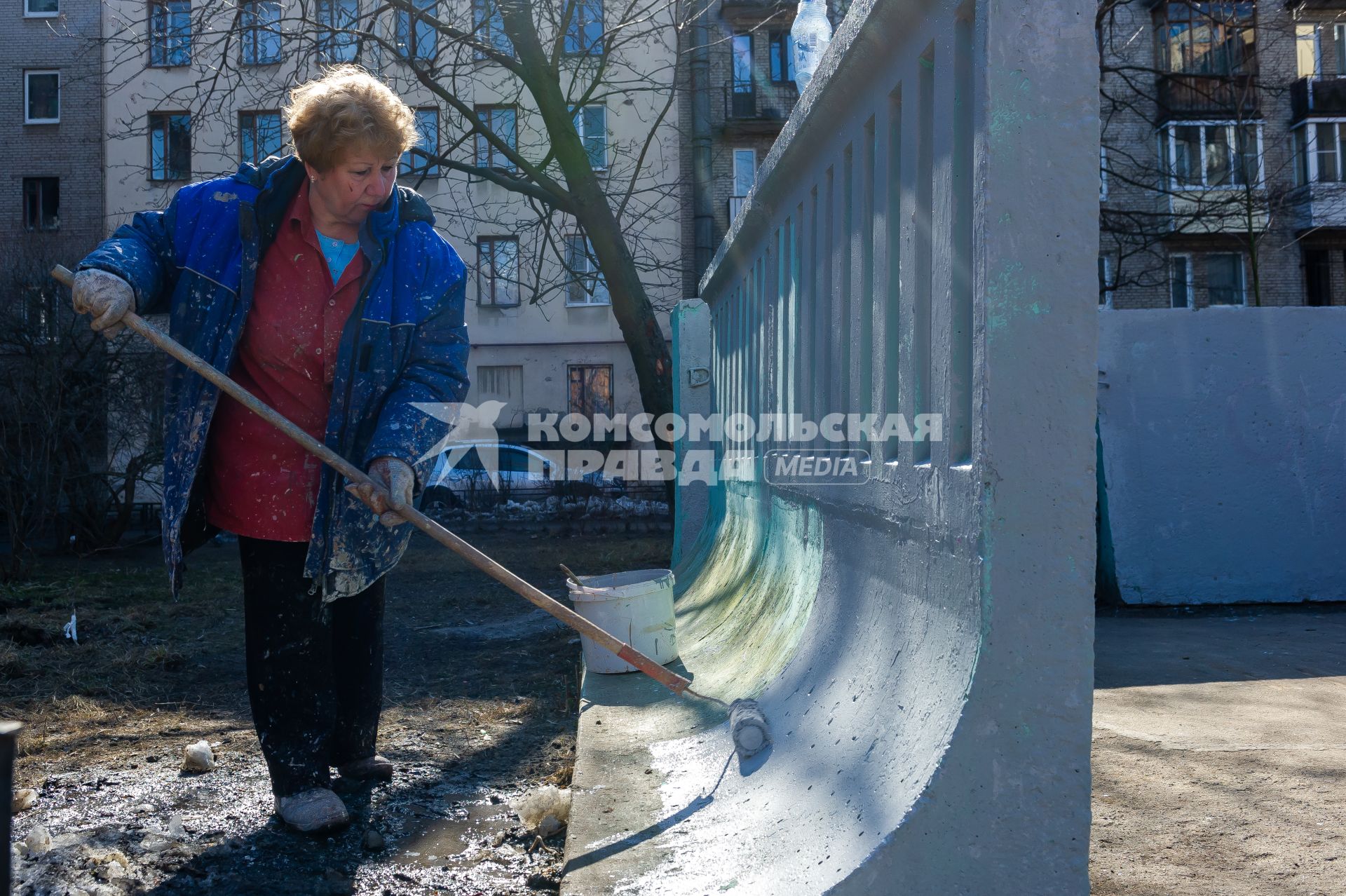 Санкт-Петербург. Сотрудник ЖКХ красит забор.