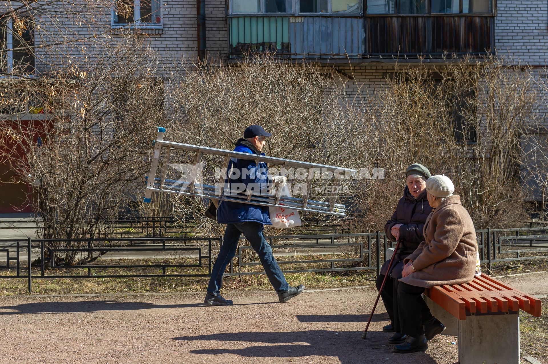 Санкт-Петербург. Сотрудник ЖКХ с лестницей во дворе дома.