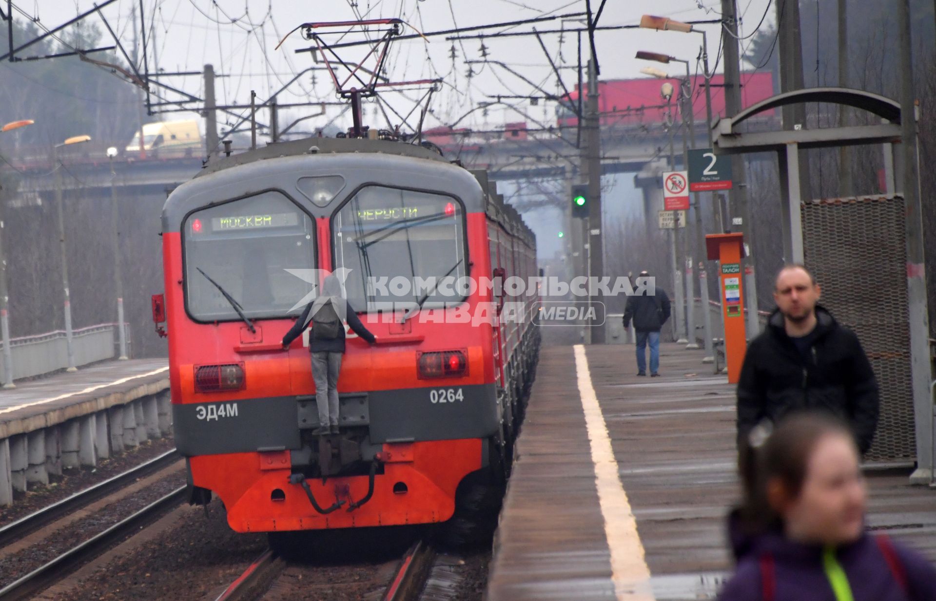 Москва.  Молодой человек `зацепер `прикрепился к последнему вагону электрички на одной из пригородных платформ.
`