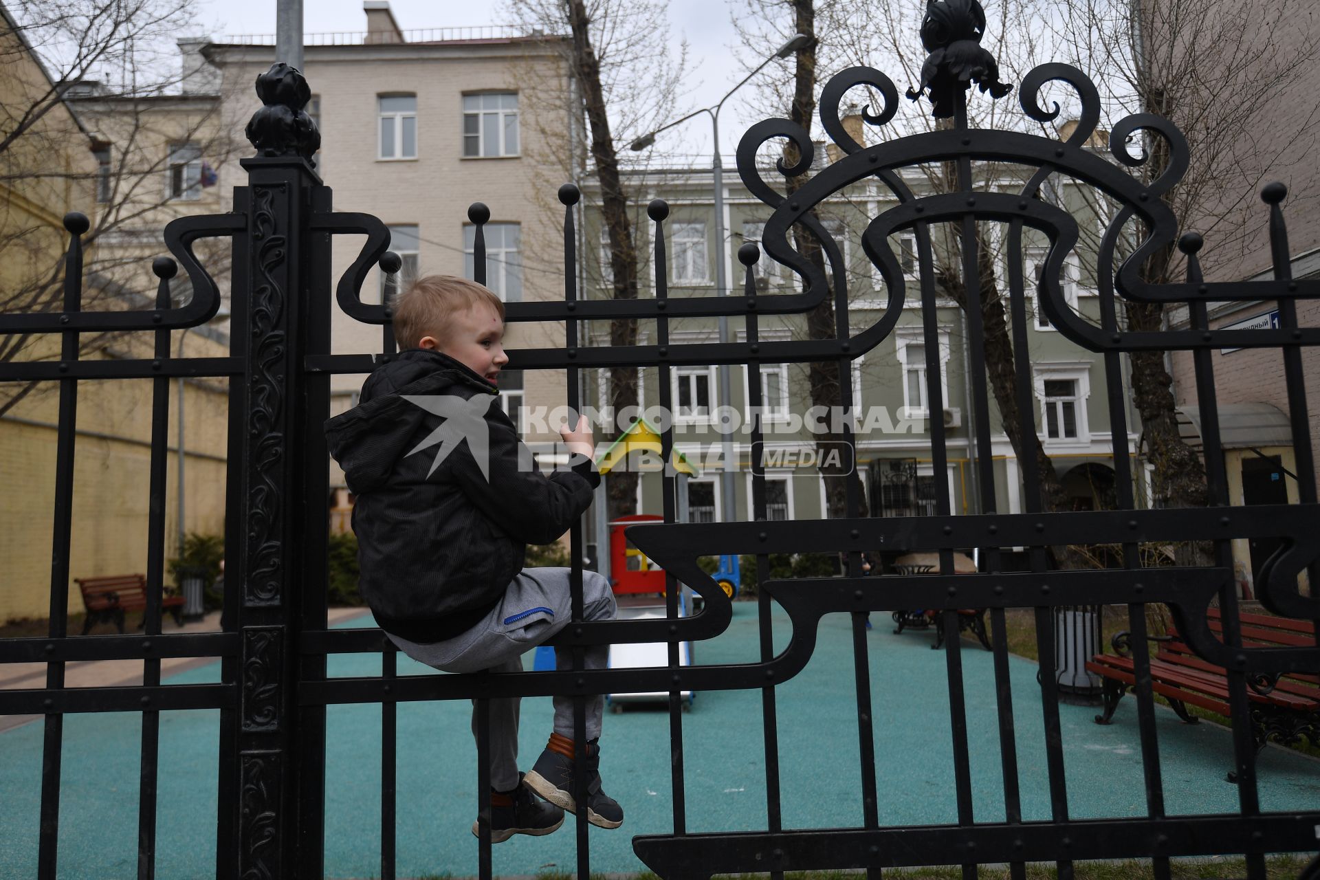 Москва. Мальчик сидит на заборе.