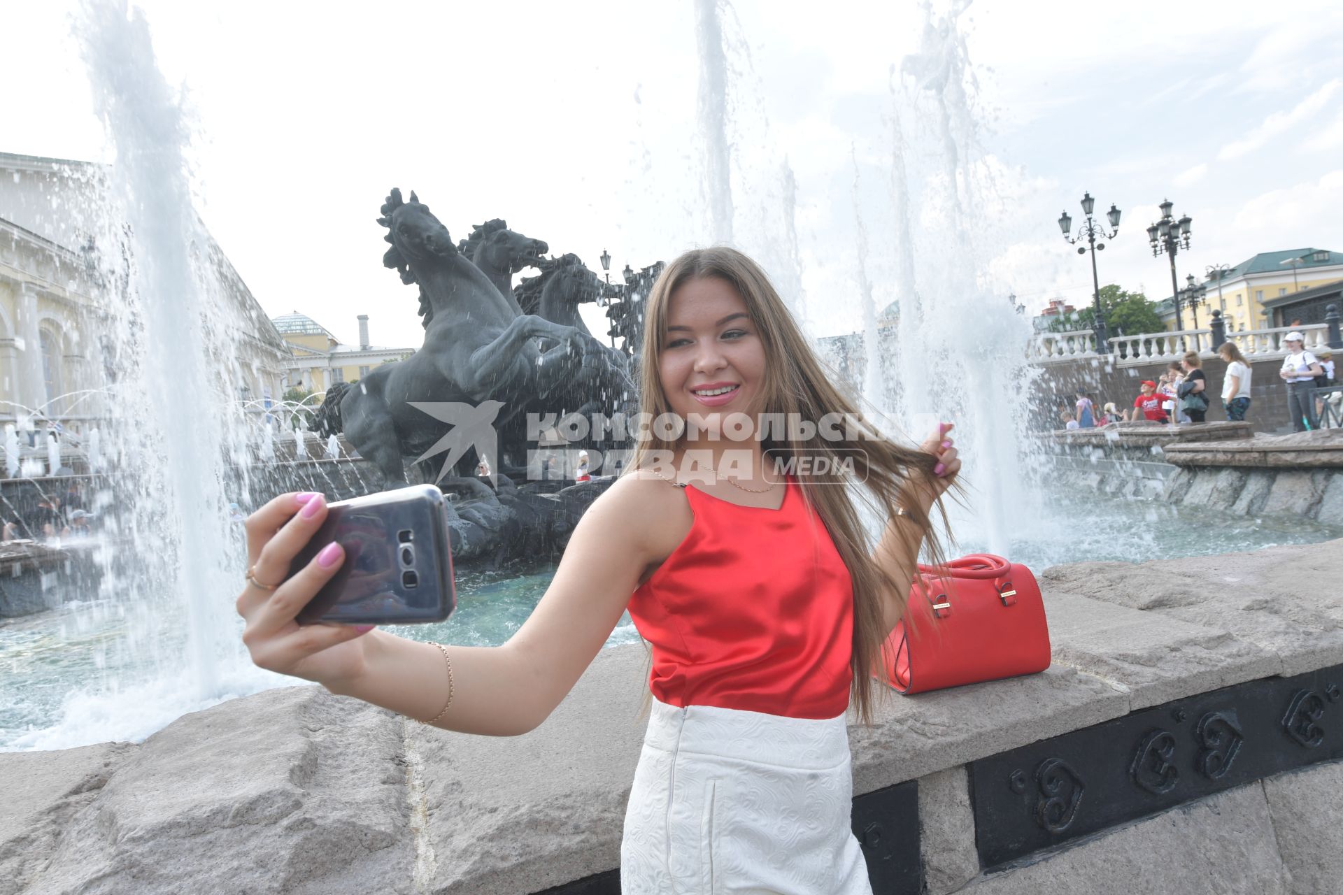 Москва.  Девушка фотографируется  у фонтанов на Манежной площади.