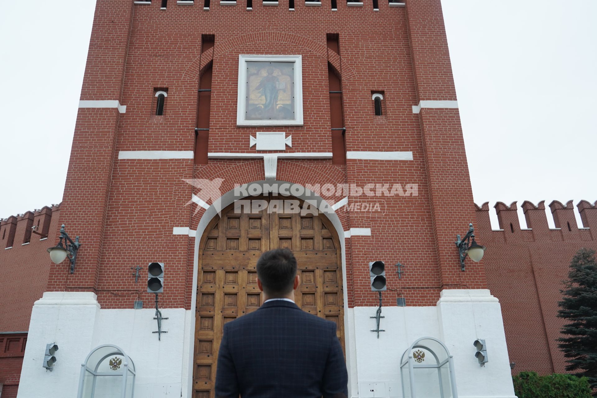 Москва.  Мужчина в костюме на Красной площади смотрит на  ворота Спасской башни Кремля.