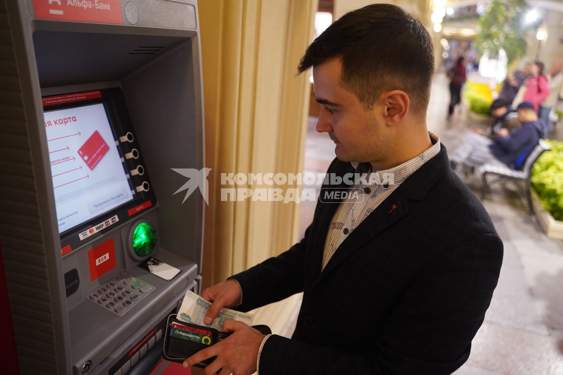 Москва.  Мужчина в костюме у  банкомата в магазине ГУМ на Красной площади.