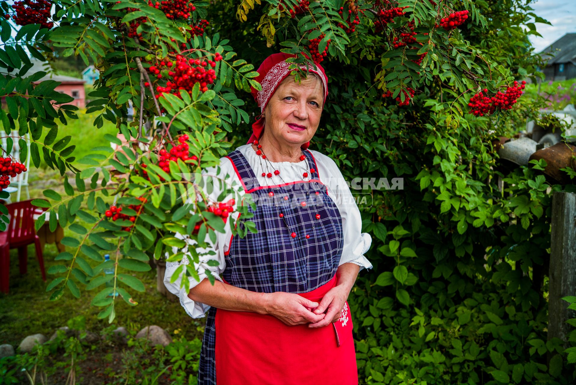 Республика Карелия, деревня Корза. Местная жительница в национальном карельском костюме на улице деревни.
