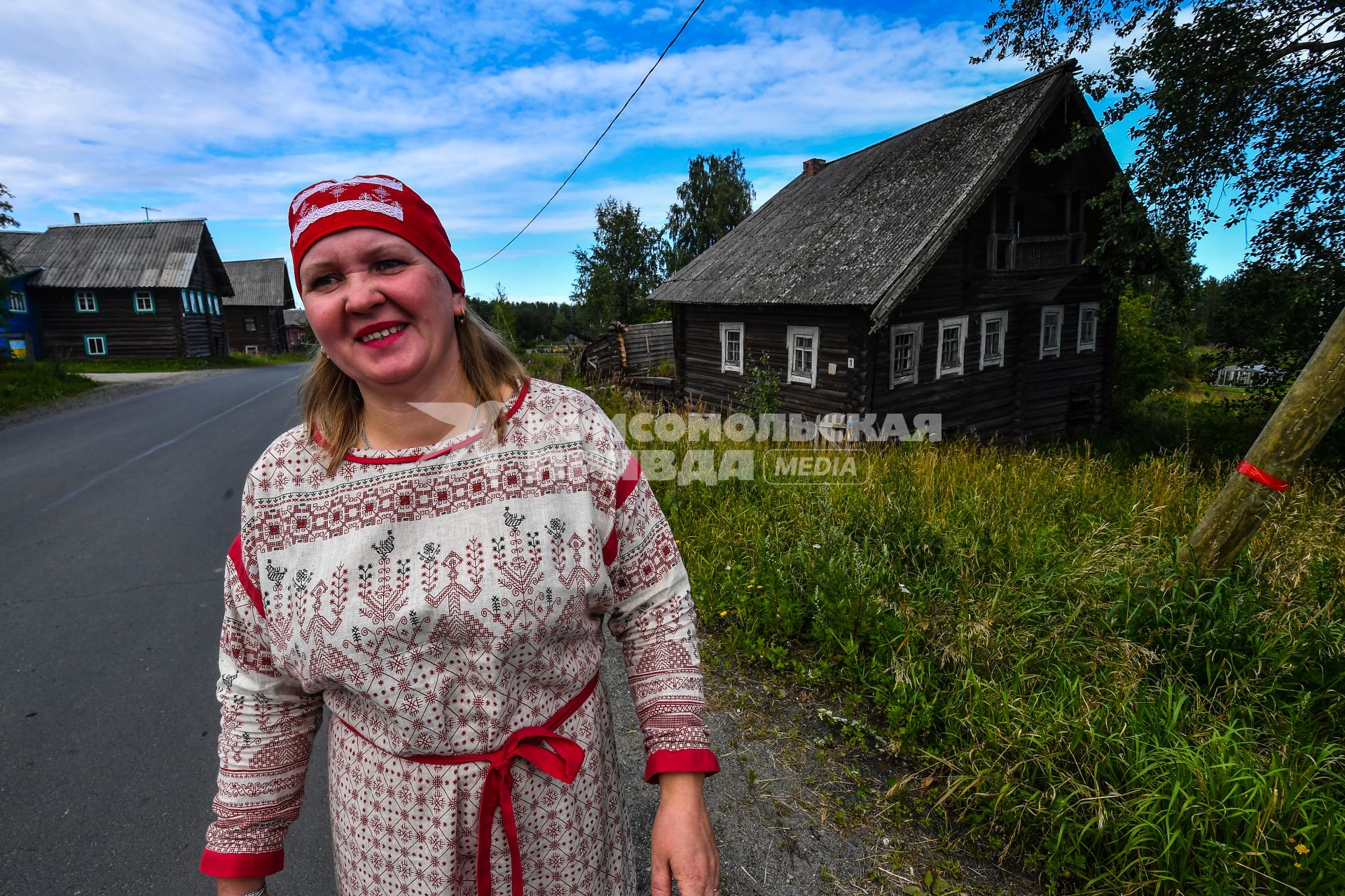 Республика Карелия, деревня Корза. Местная жительница в национальном карельском костюме на улице деревни.