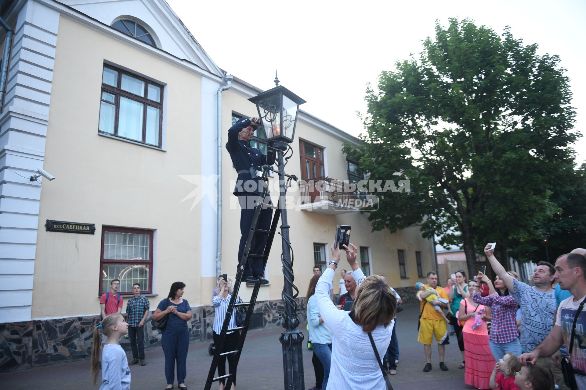 Беларусь, Брест.  Фонарщик зажигает фонарь на улице города.