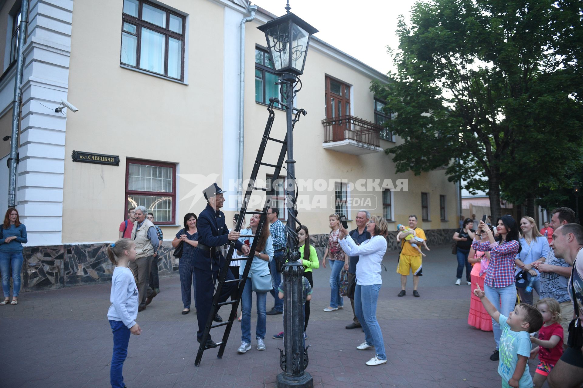 Беларусь, Брест.  Фонарщик зажигает фонарь на улице города.