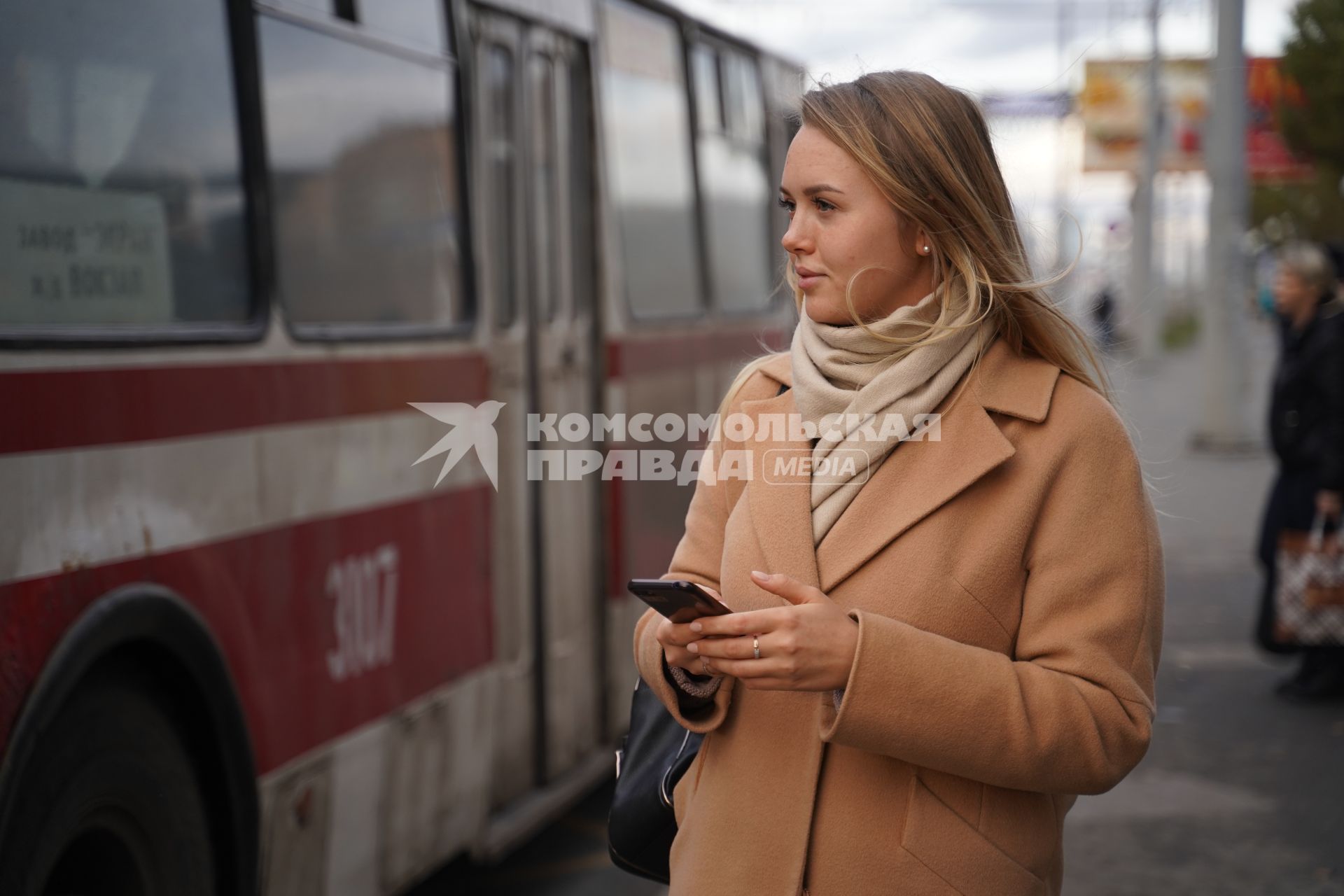 Самара. Девушка с мобильным телефоном на автобусной остановке.