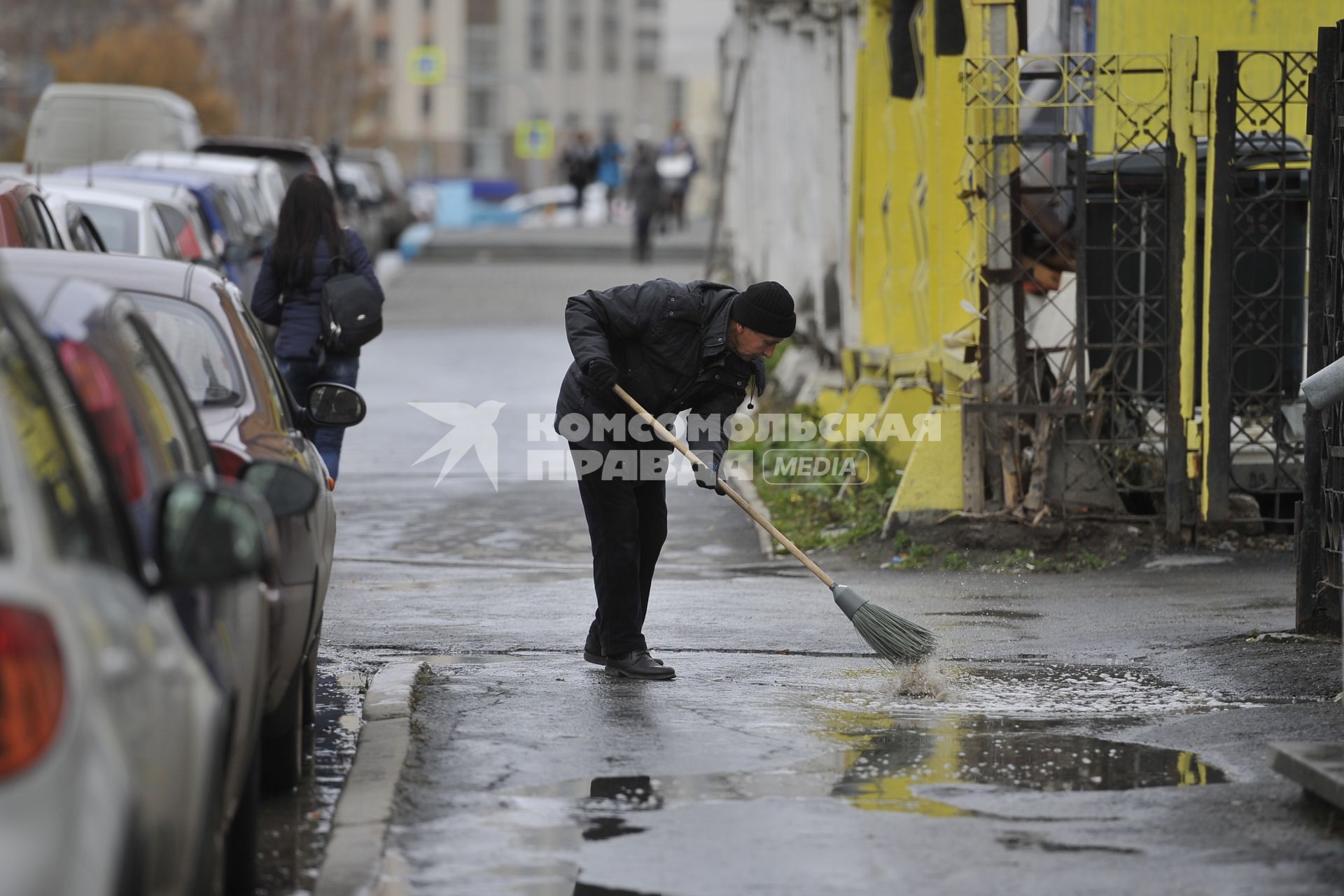 Екатеринбург. Дворник сметает лужу с тротуара