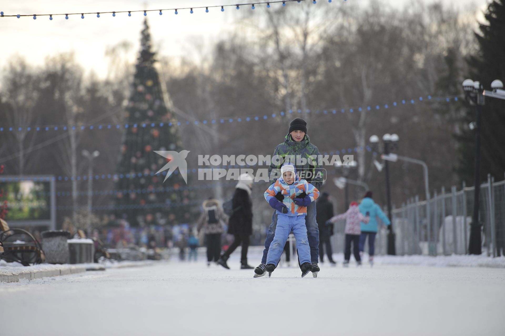 Екатеринбург. Мужчина с ребенком катаются на коньках на катке