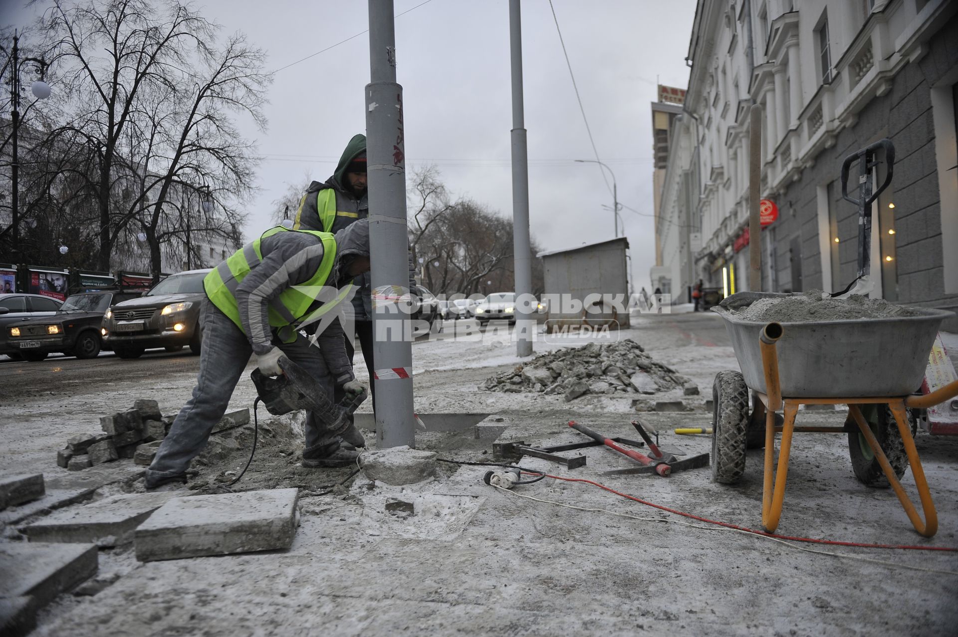 Екатеринбург. Рабочие в снег укладывают тротуарную гранитную плитку