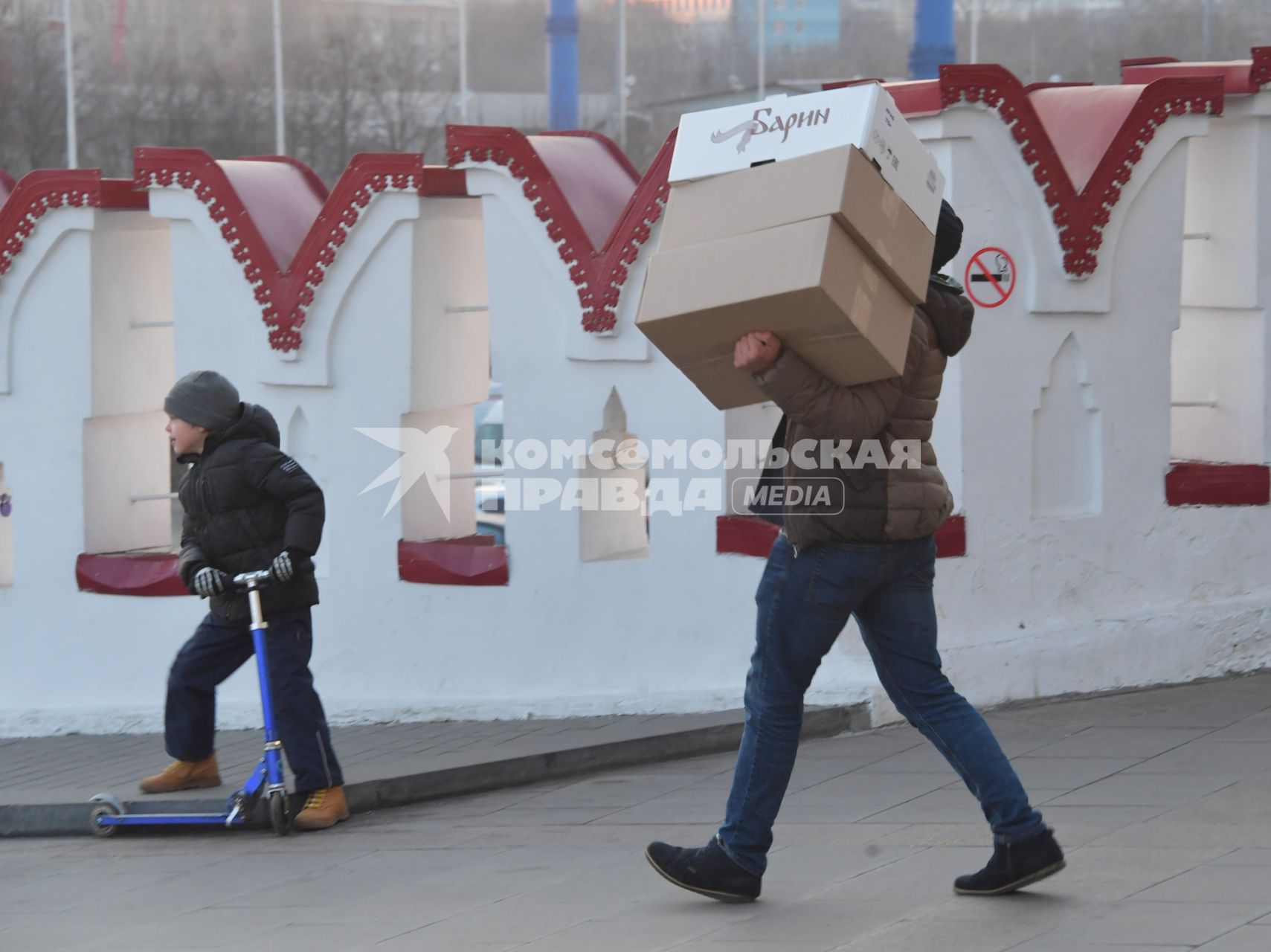 Москва. Мужчина несет коробки по пешеходному мосту Измайловского кремля.