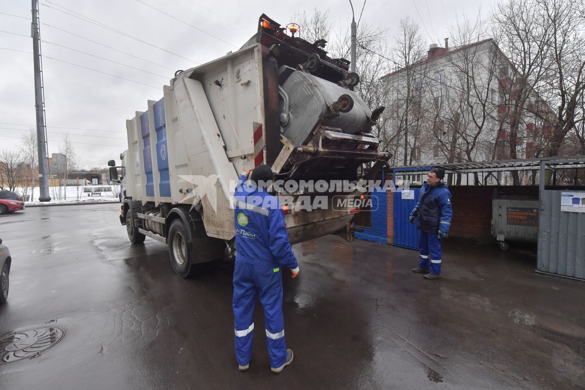 Москва. Рабочие грузят мусорный контейнер.