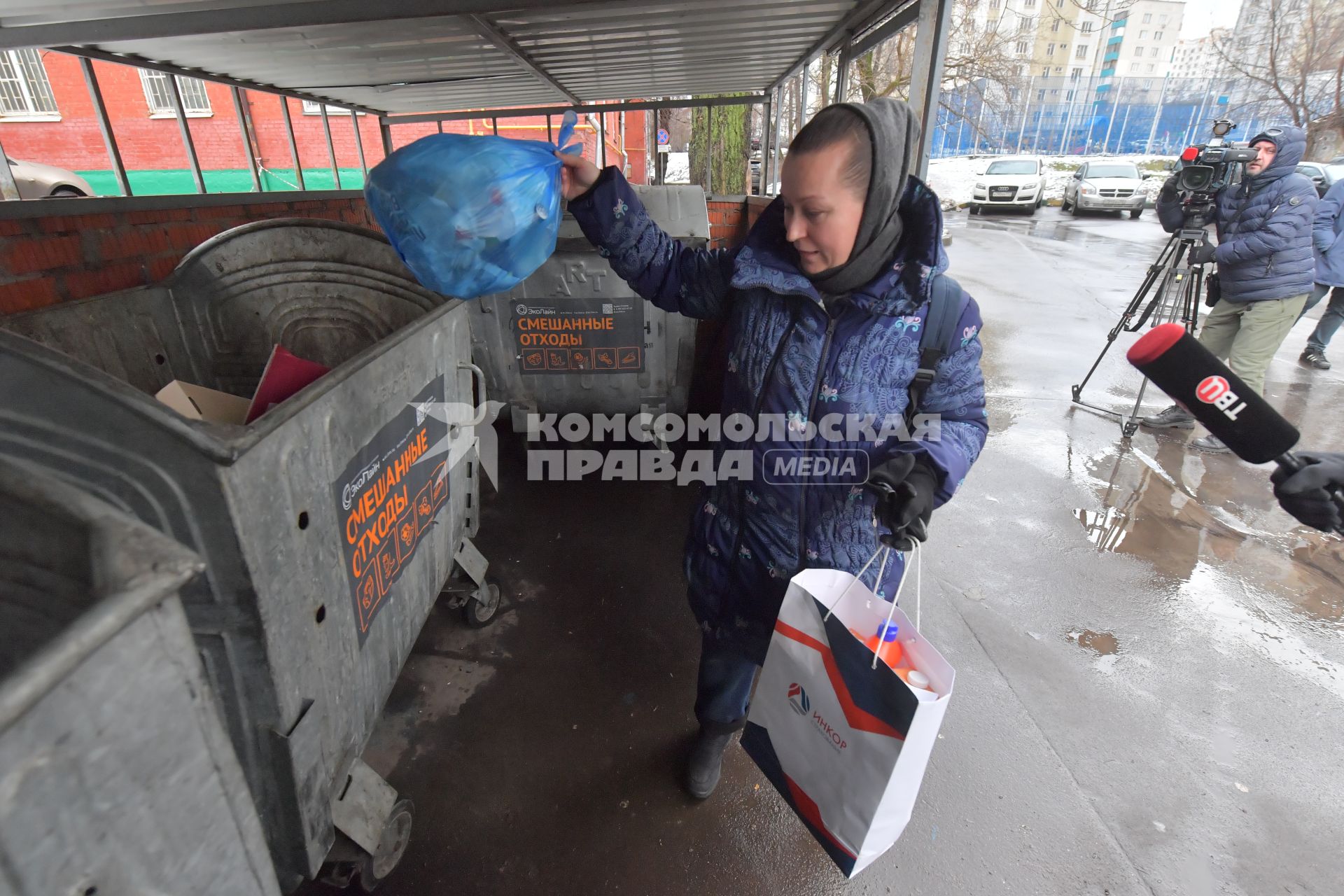 Москва. Женщина выбрасывает мусор в уличный контейнер.