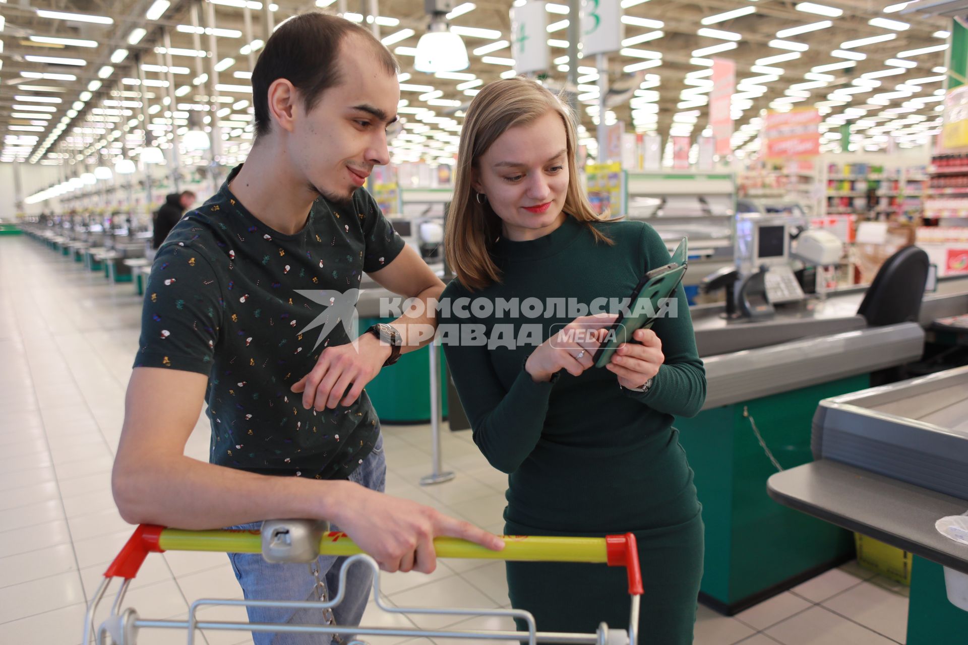 Красноярск. Молодые люди в магазине с продуктовой тележкой.