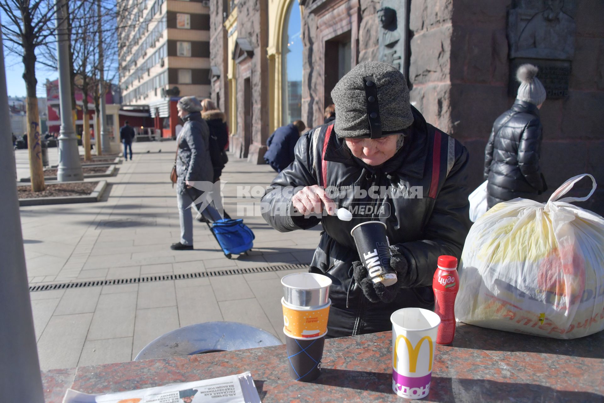 Москва. Пожилая женщина ест  на Тверской улице.