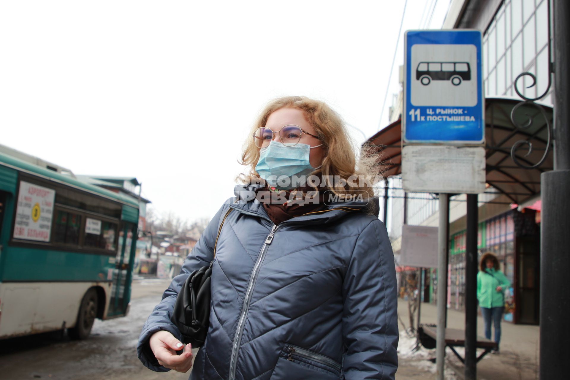 Иркутск. Девушка в медицинской маске  на остановке  общественного транспорта.
