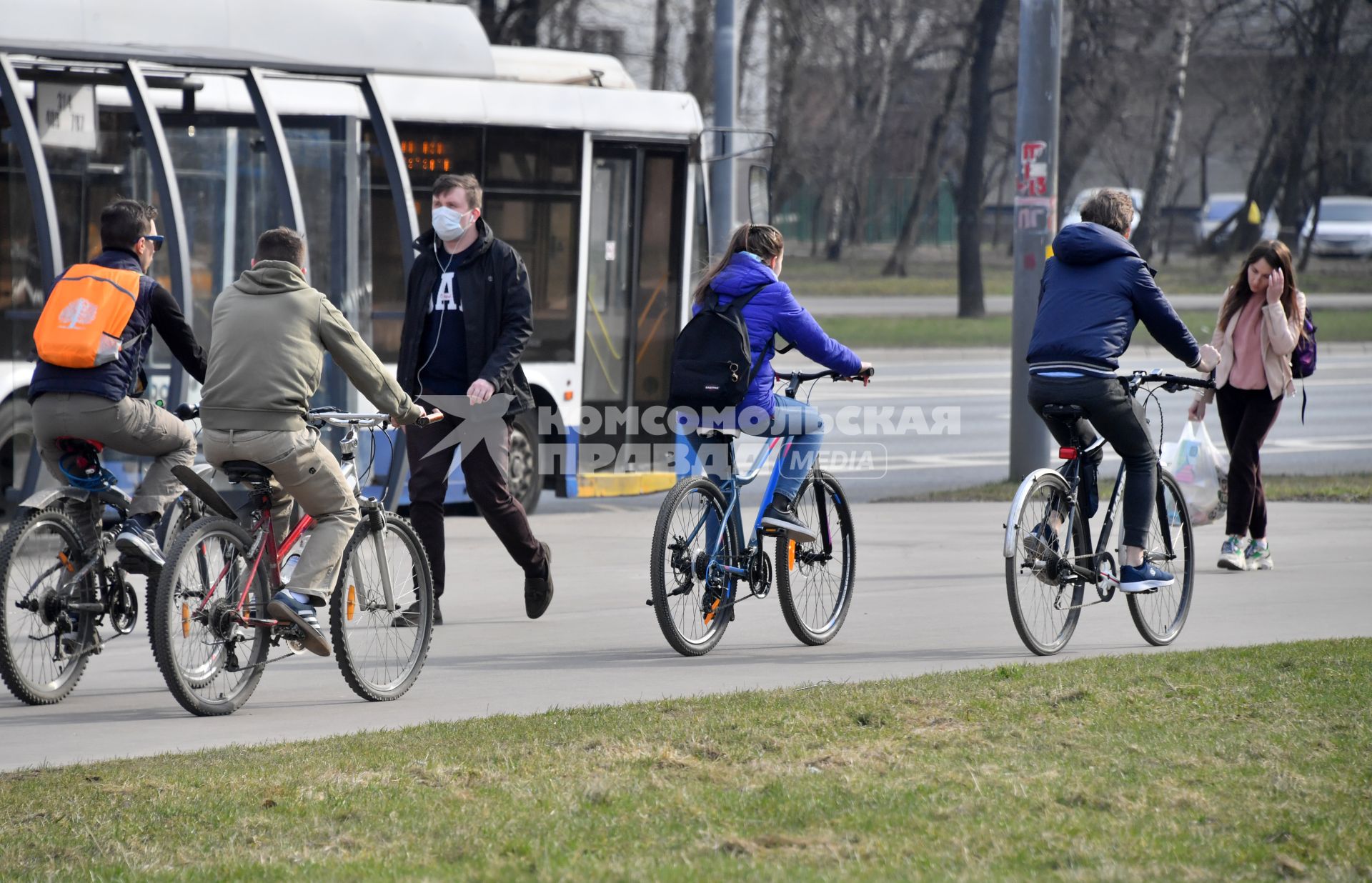 Москва.   Велосипедисты и мужчина в медицинской маске на улице города.