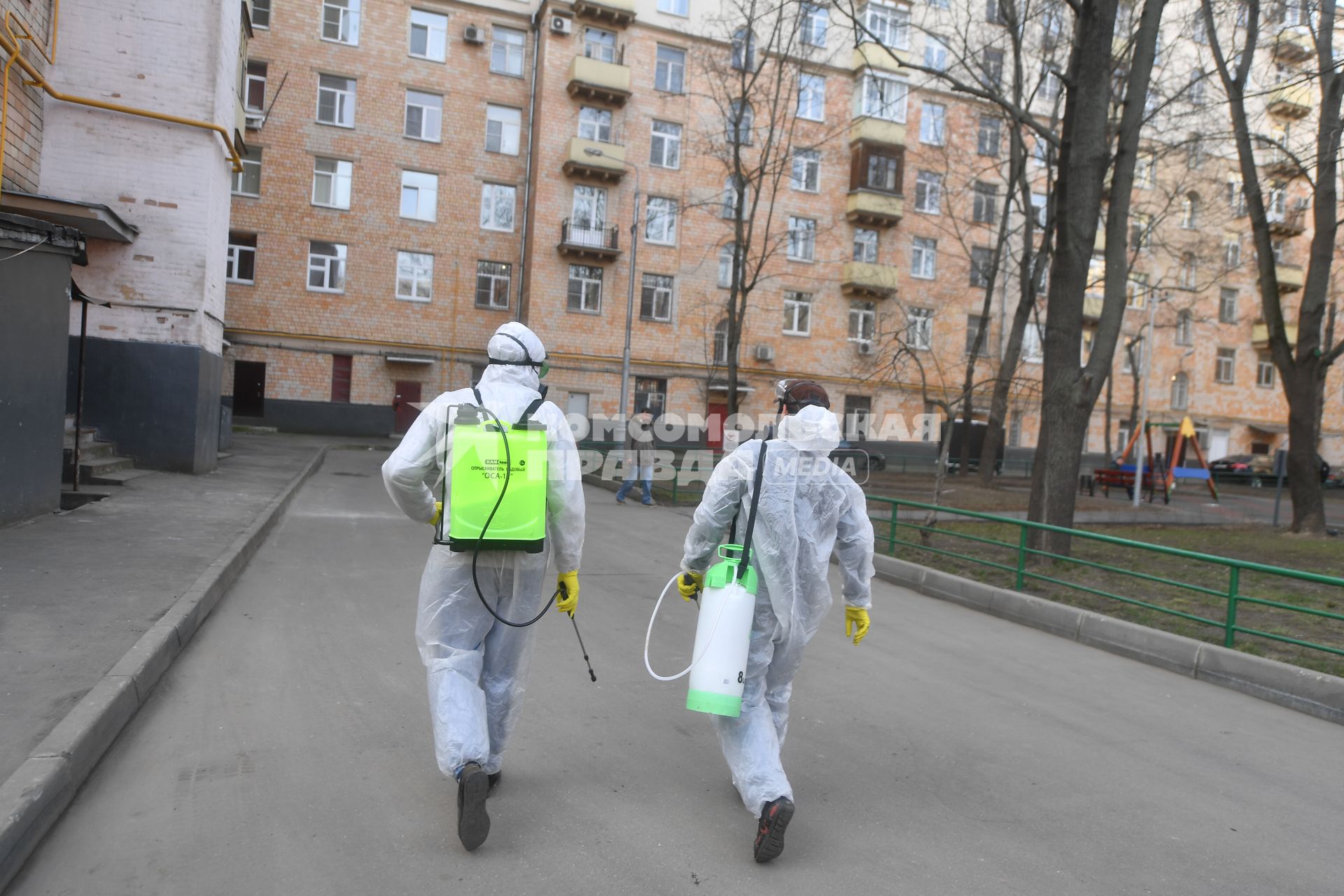 Москва. Сотрудники коммунальной службы в защитных костюмах  во время дезинфекции двора жилого дома.