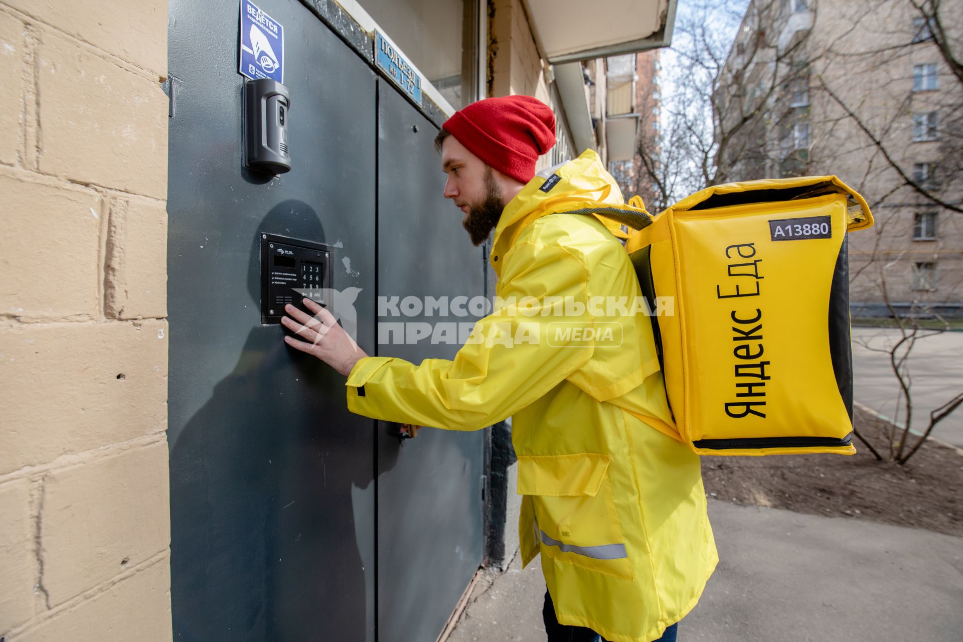 Москва.   Сотрудник сервиса по доставке еды `Яндекс Еда` у подъезда дома.