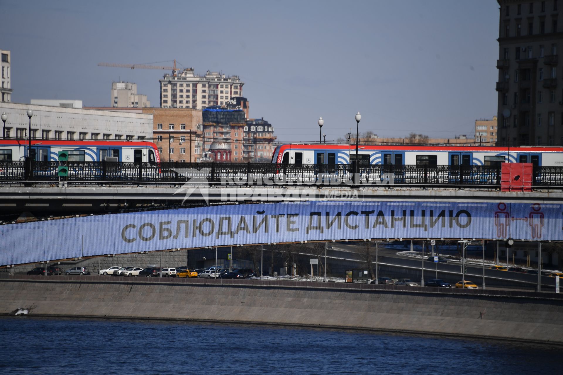 Москва.  Плакат с призывом соблюдать дистанцию от окружающих на Смоленском метромосту.