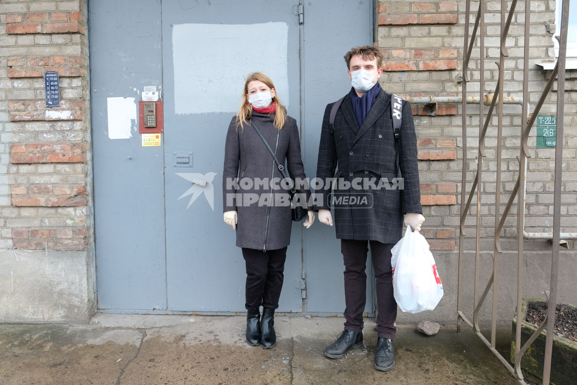 Санкт-Петербург. Молодой человек и девушка в медицинских масках у подъезда дома.