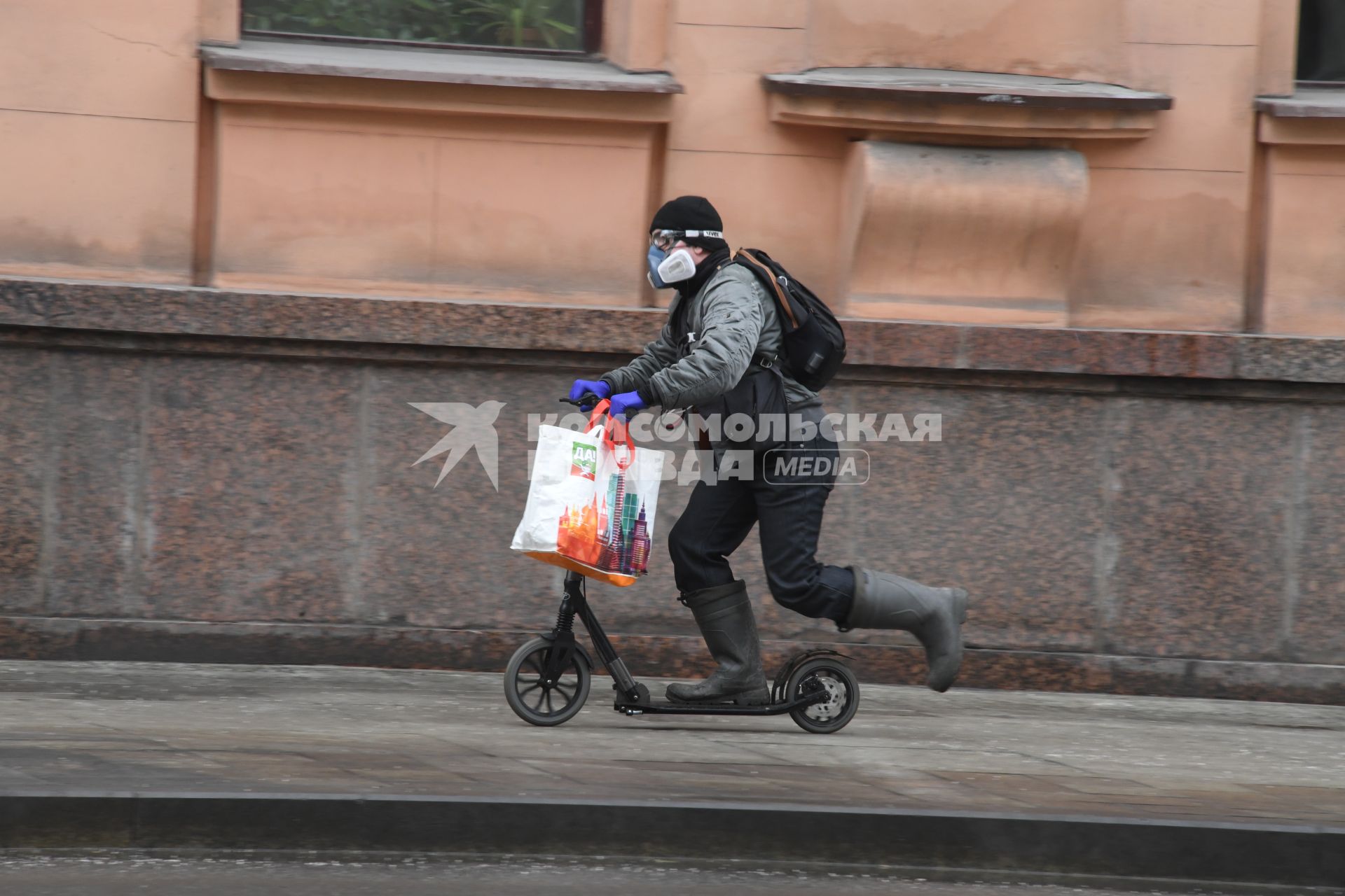 Москва. Мужчина в медицинской маске и резиновых перчатках на самокате.