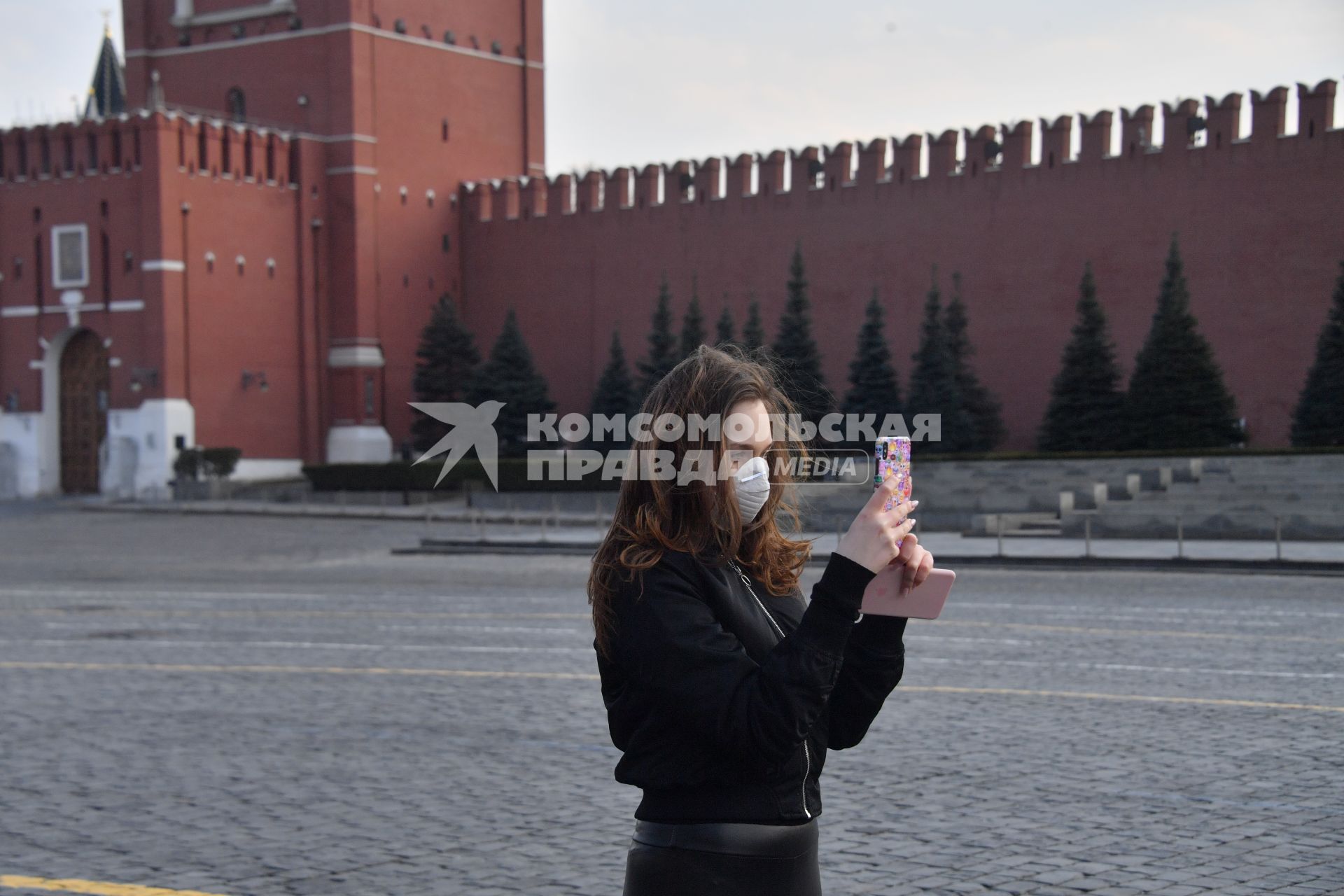 Москва.  Девушка в медицинской маске на Красной площади.