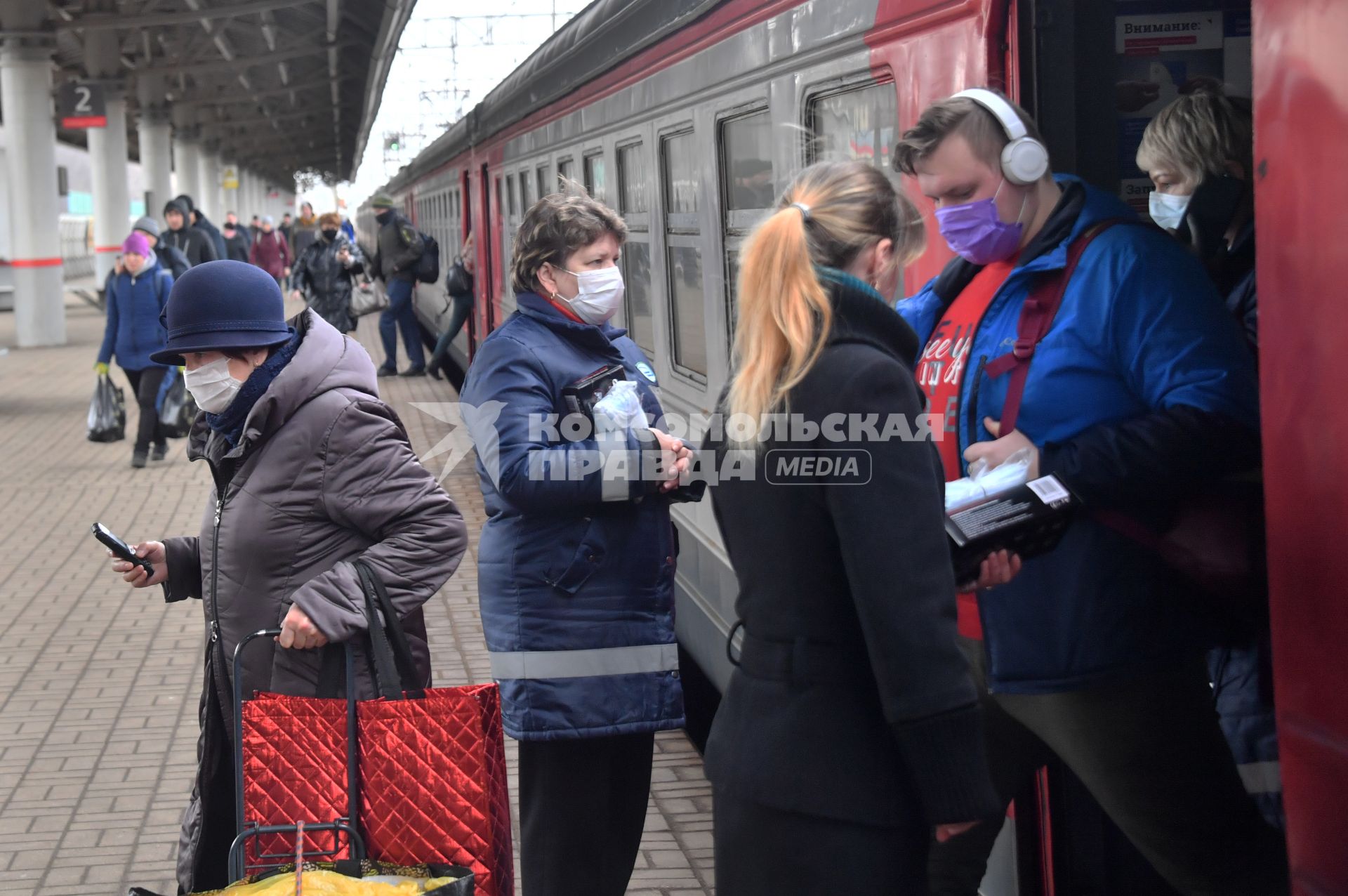 Москва.  Пассажиры в медицинских масках  выходят из вагона электрички.