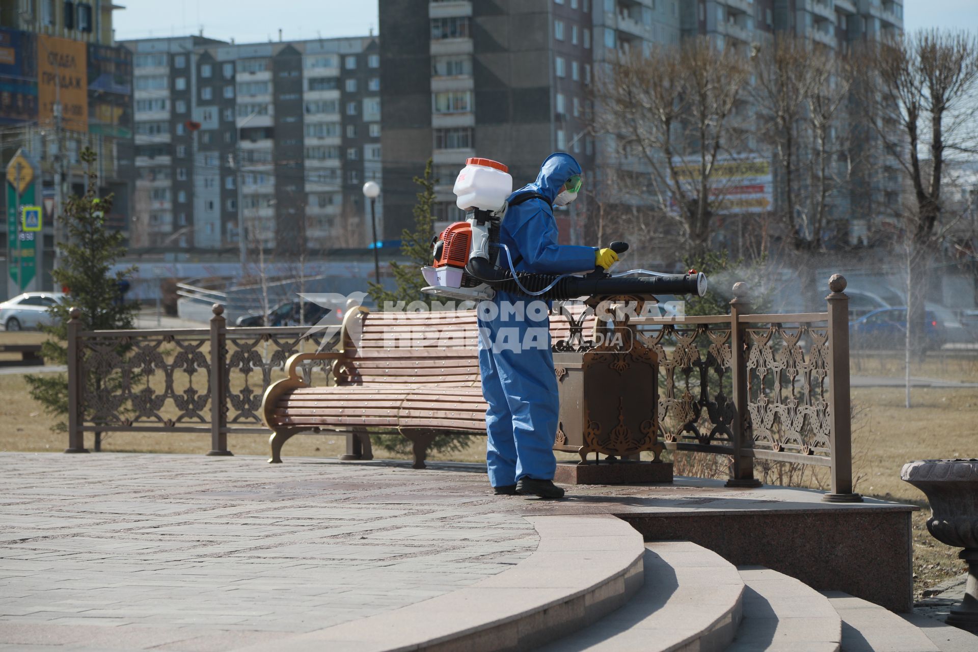 Красноярск. Сотрудник коммунальных служб обрабатывает антисептическим раствором  тротуары и скамейки.