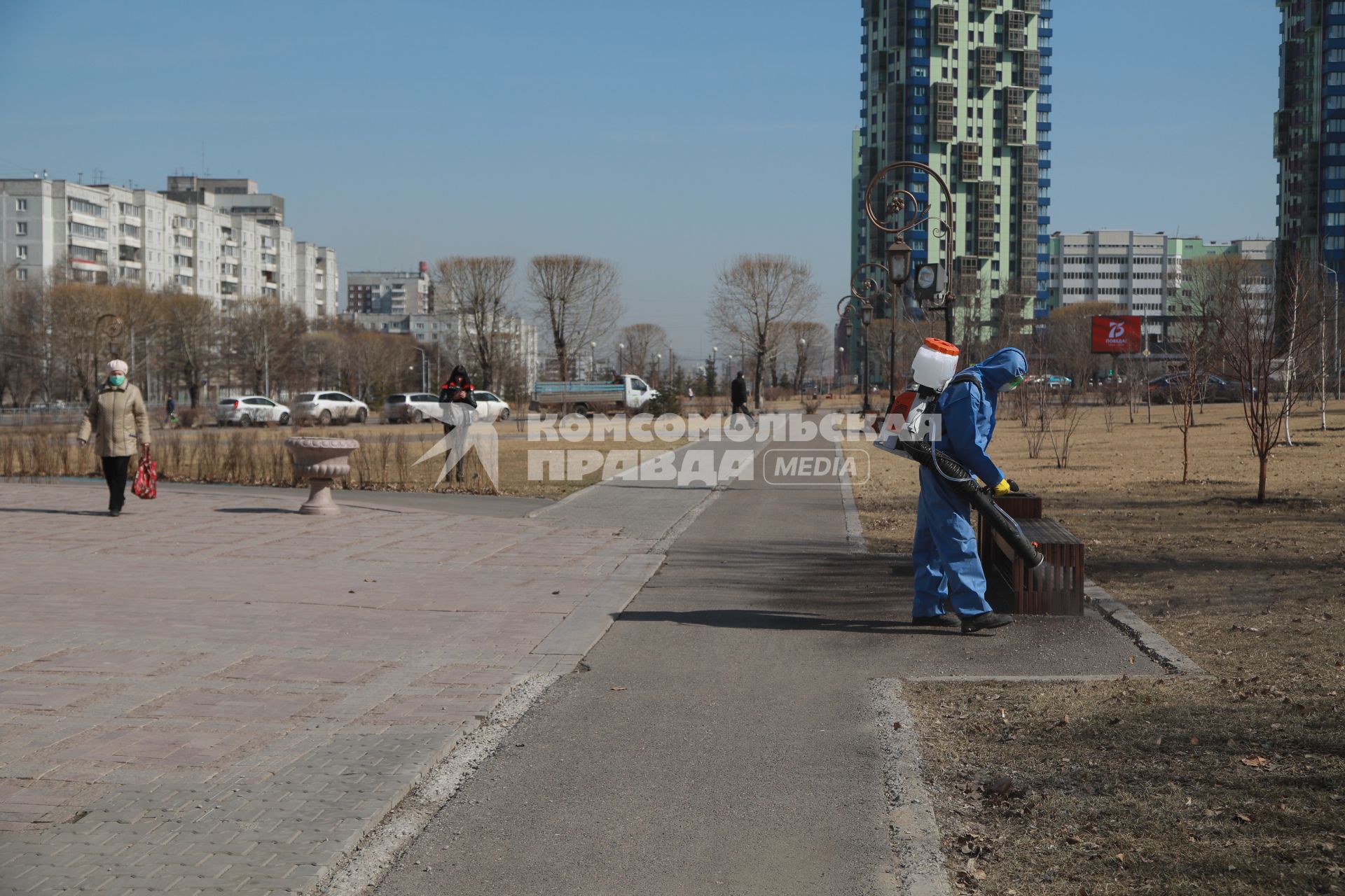 Красноярск. Сотрудник коммунальных служб обрабатывает антисептическим раствором  тротуары и скамейки.
