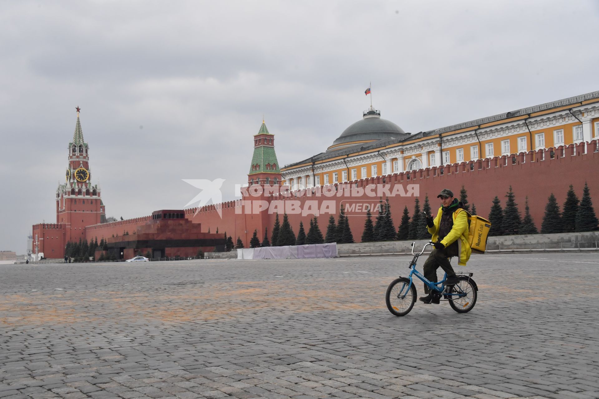 Москва. Сотрудник сервиса доставки еды `Яндекс. Еда`едет по Красной площади на велосипеде.