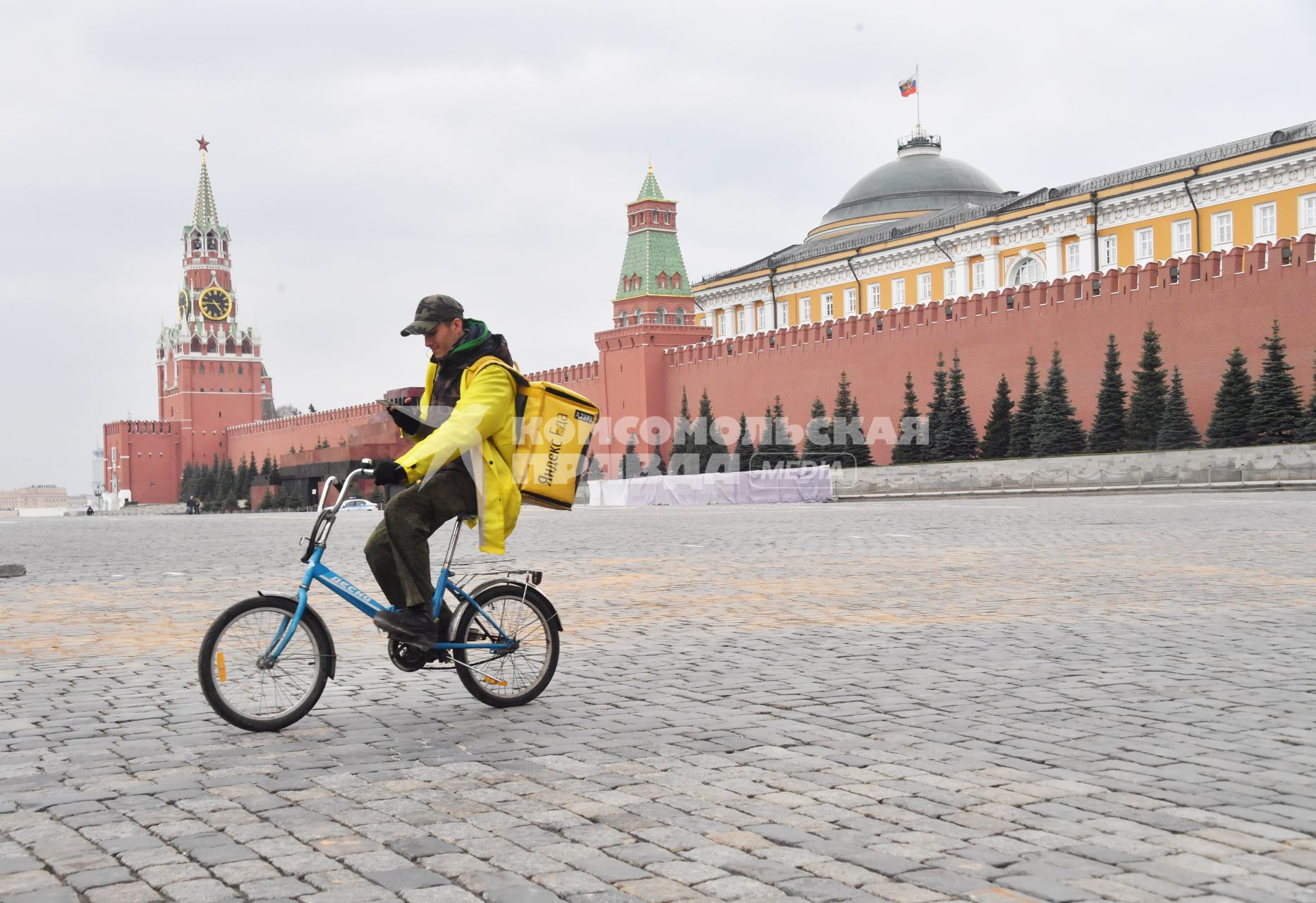 Москва. Сотрудник сервиса доставки еды `Яндекс. Еда`едет по Красной площади на велосипеде.