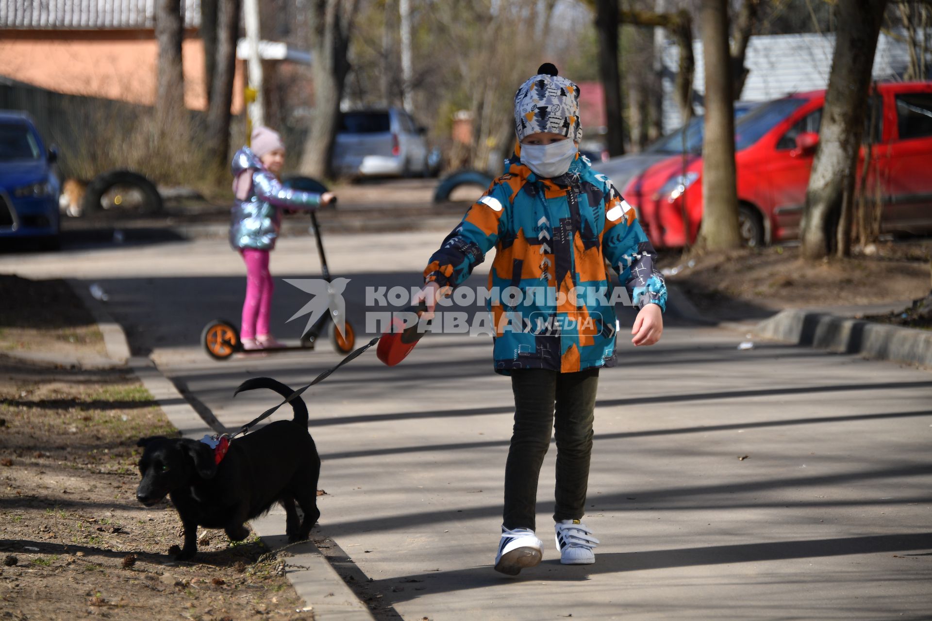 Москва.   Мальчик в медицинской маске гуляет с собакой во дворе.