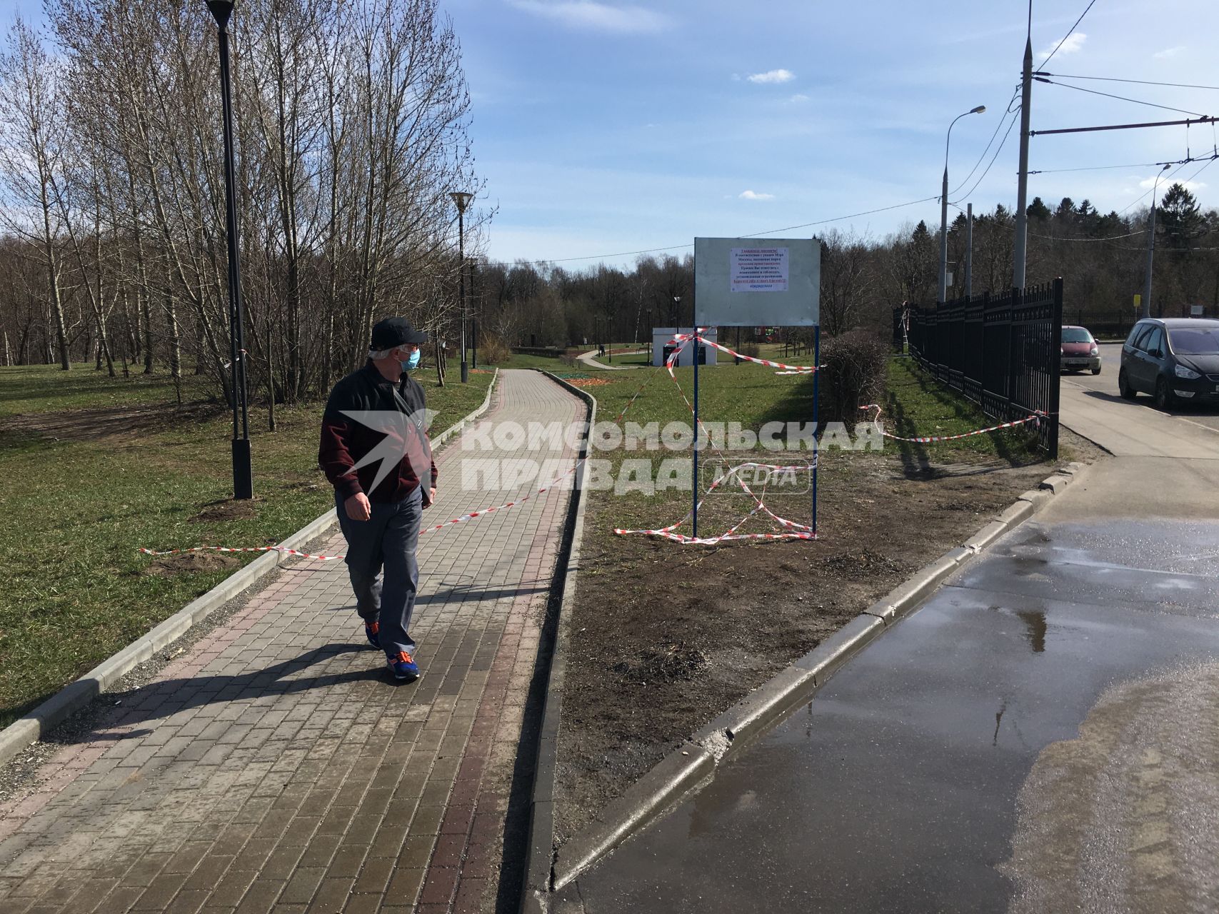 Москва. Мужчина в медицинской маске гуляет в закрытом парке.