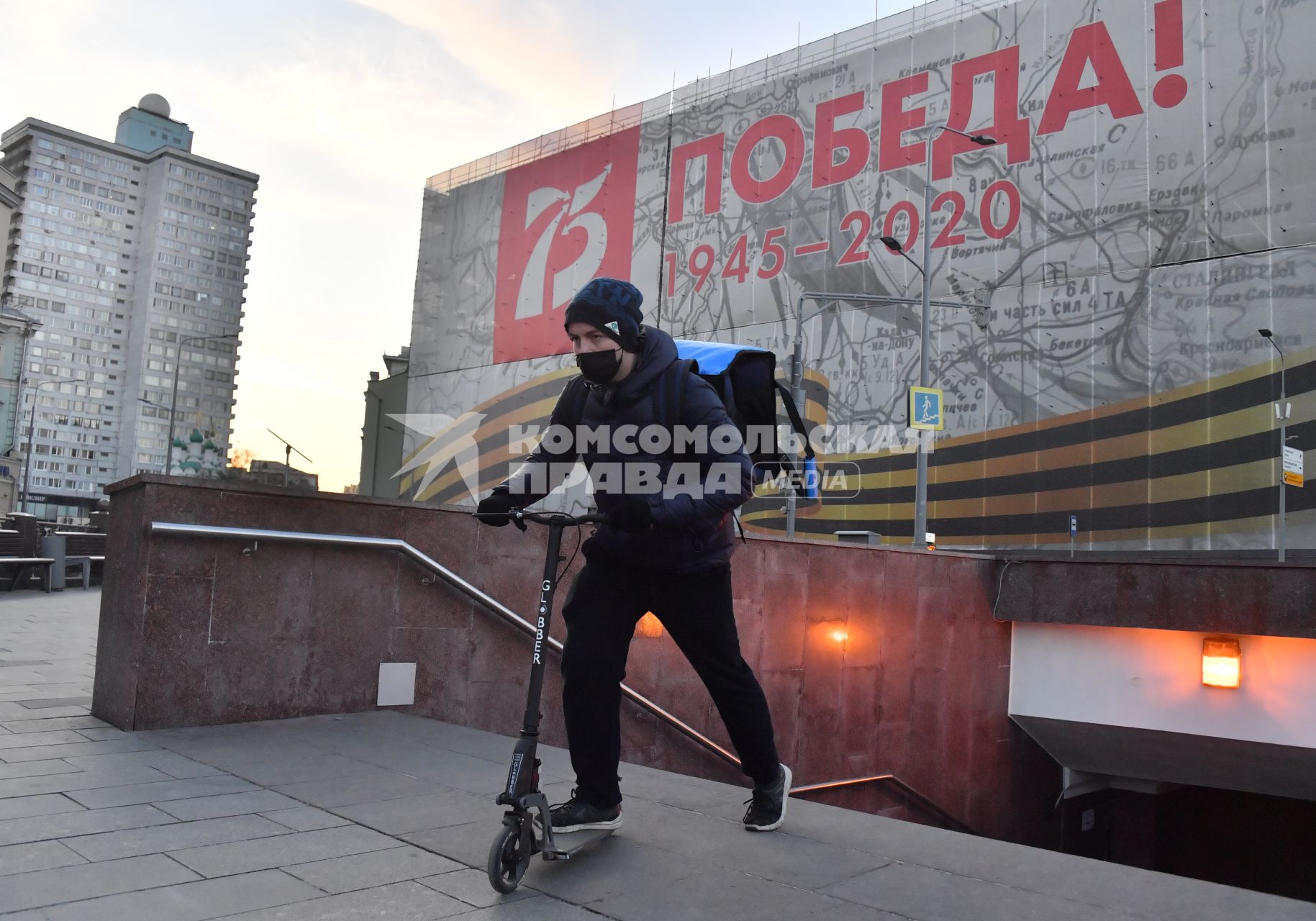 Москва. Сотрудник сервиса доставки еды на самокате и в медицинской маске.