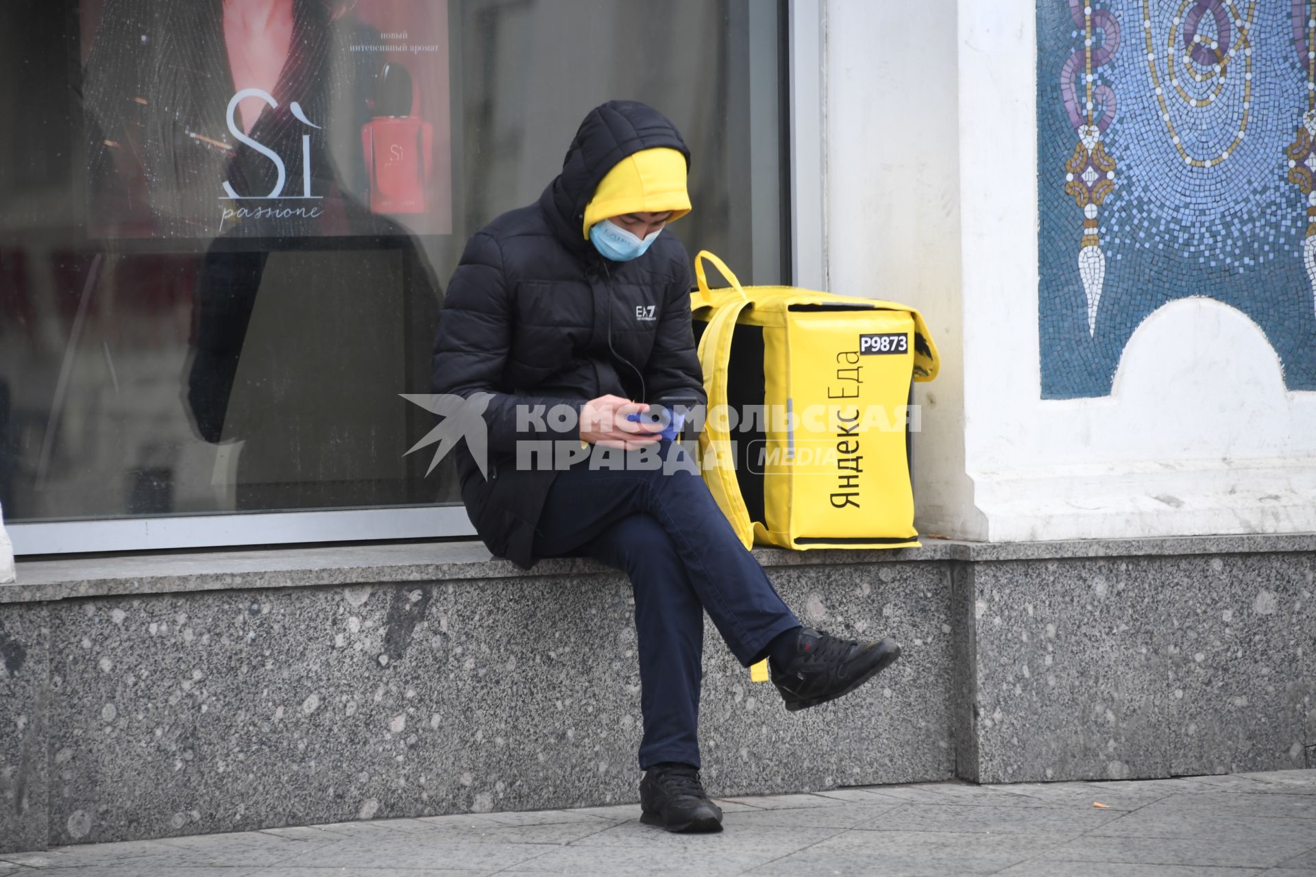 Москва.  Сотрудник сервиса доставки еды с мобильным телефоном.