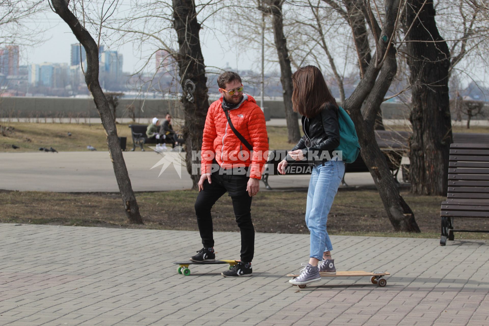 Иркутск.  Мужчина и девушка катаются на скейтбордах.