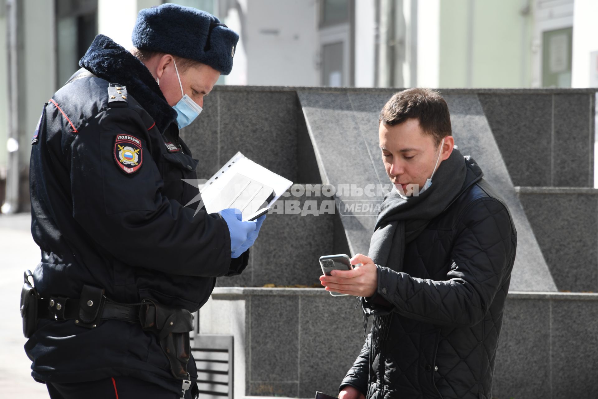 Москва. Сотрудник полиции проверяет документы у прохожих.