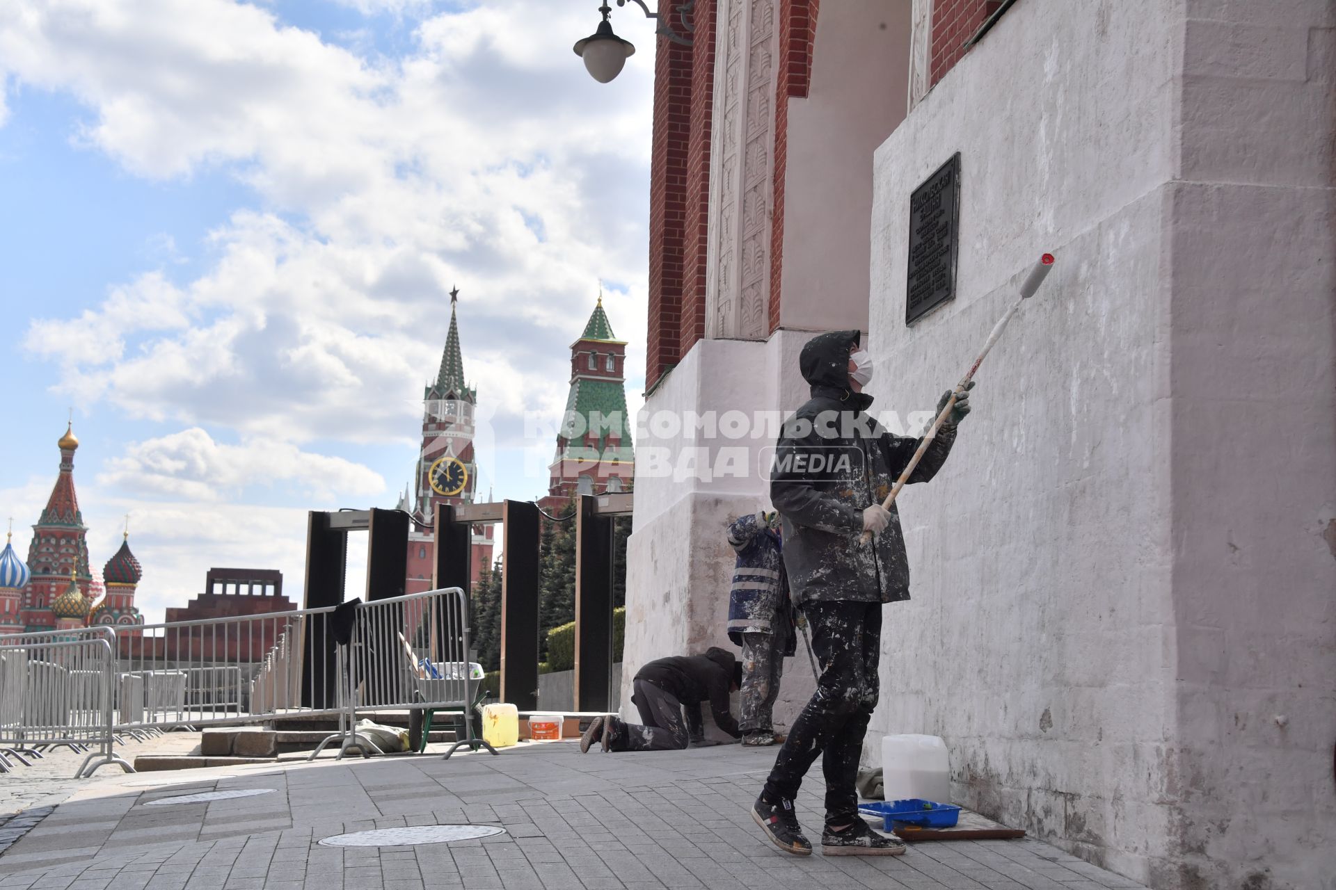 Москва. Рабочий в медицинской маске красит стену дома.