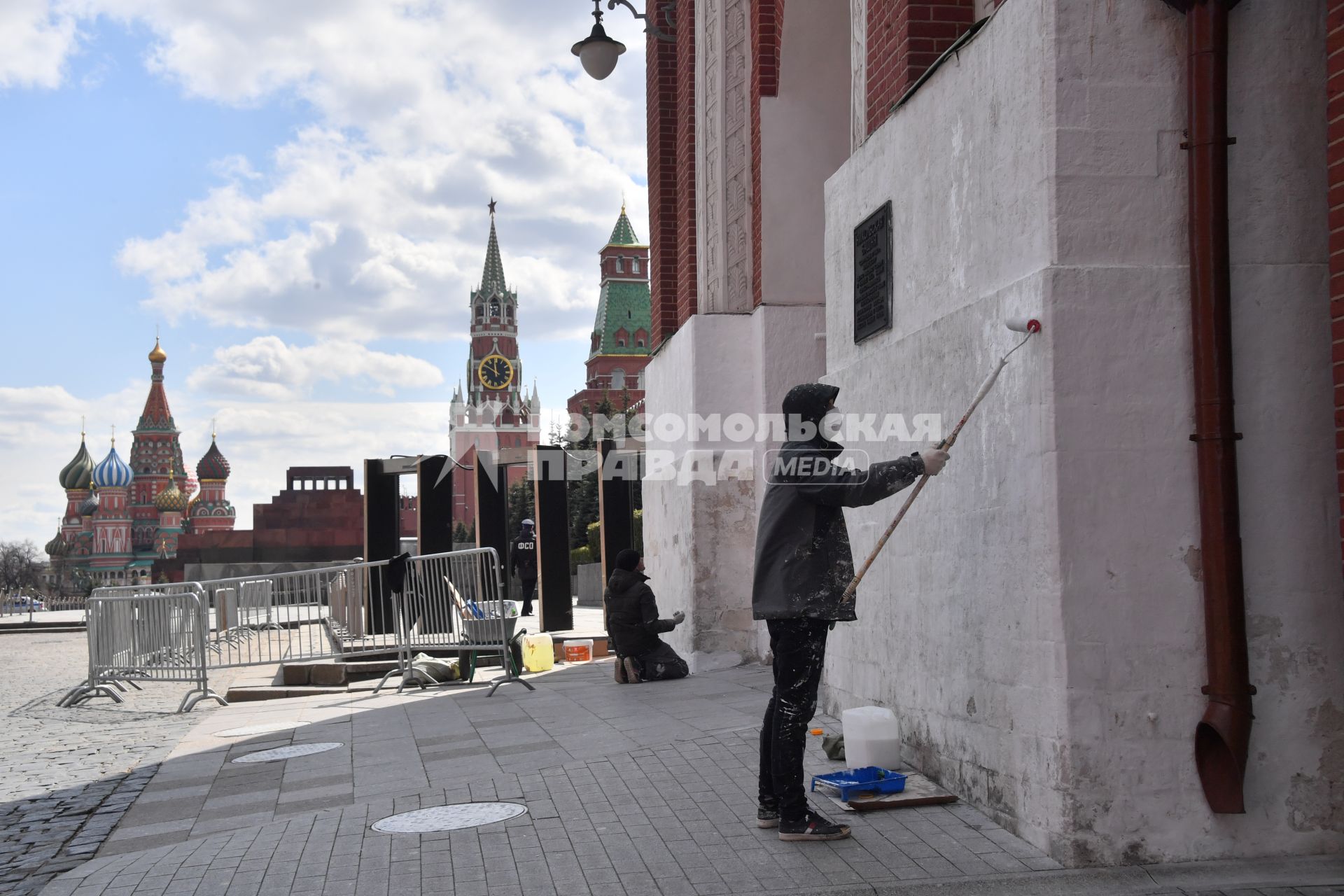 Москва. Рабочий в медицинской маске красит стену дома.