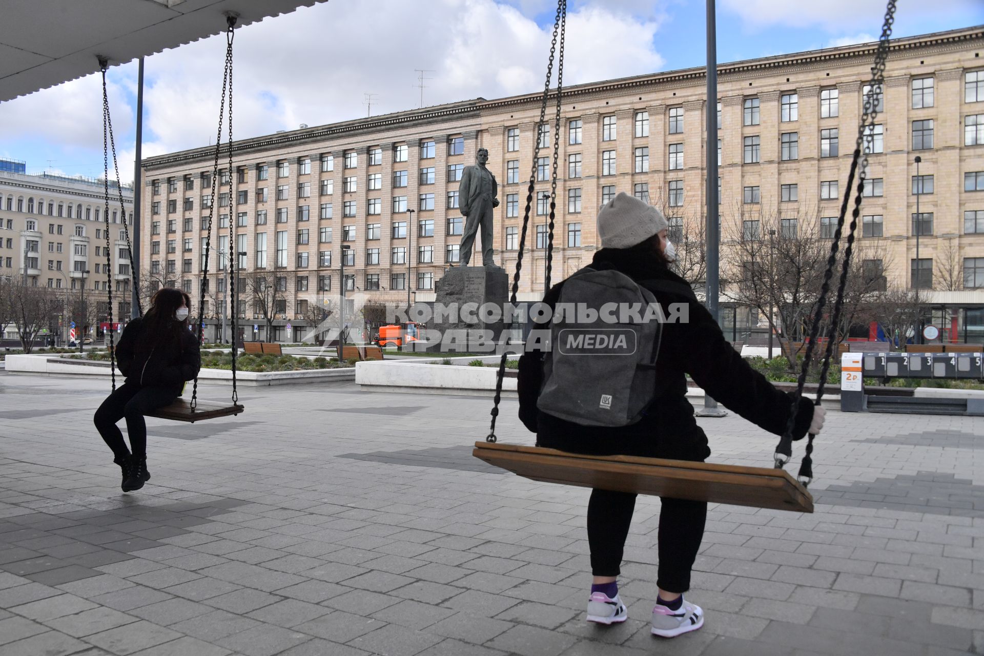 Москва. Молодые люди на Триумфальной площади  сидят на качелях.