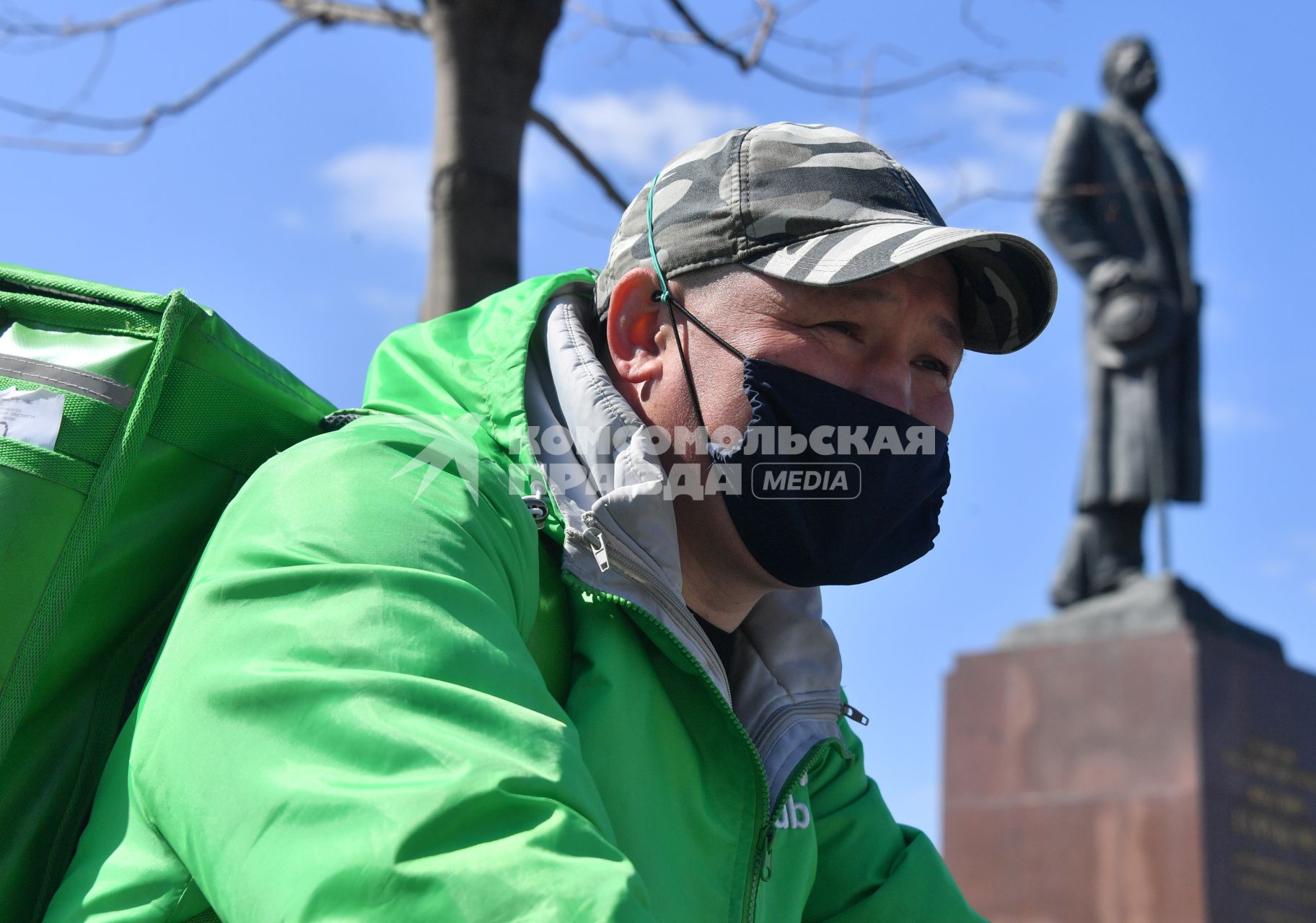 Москва. Сотрудник сервиса доставки еды  сидит на скамейке.