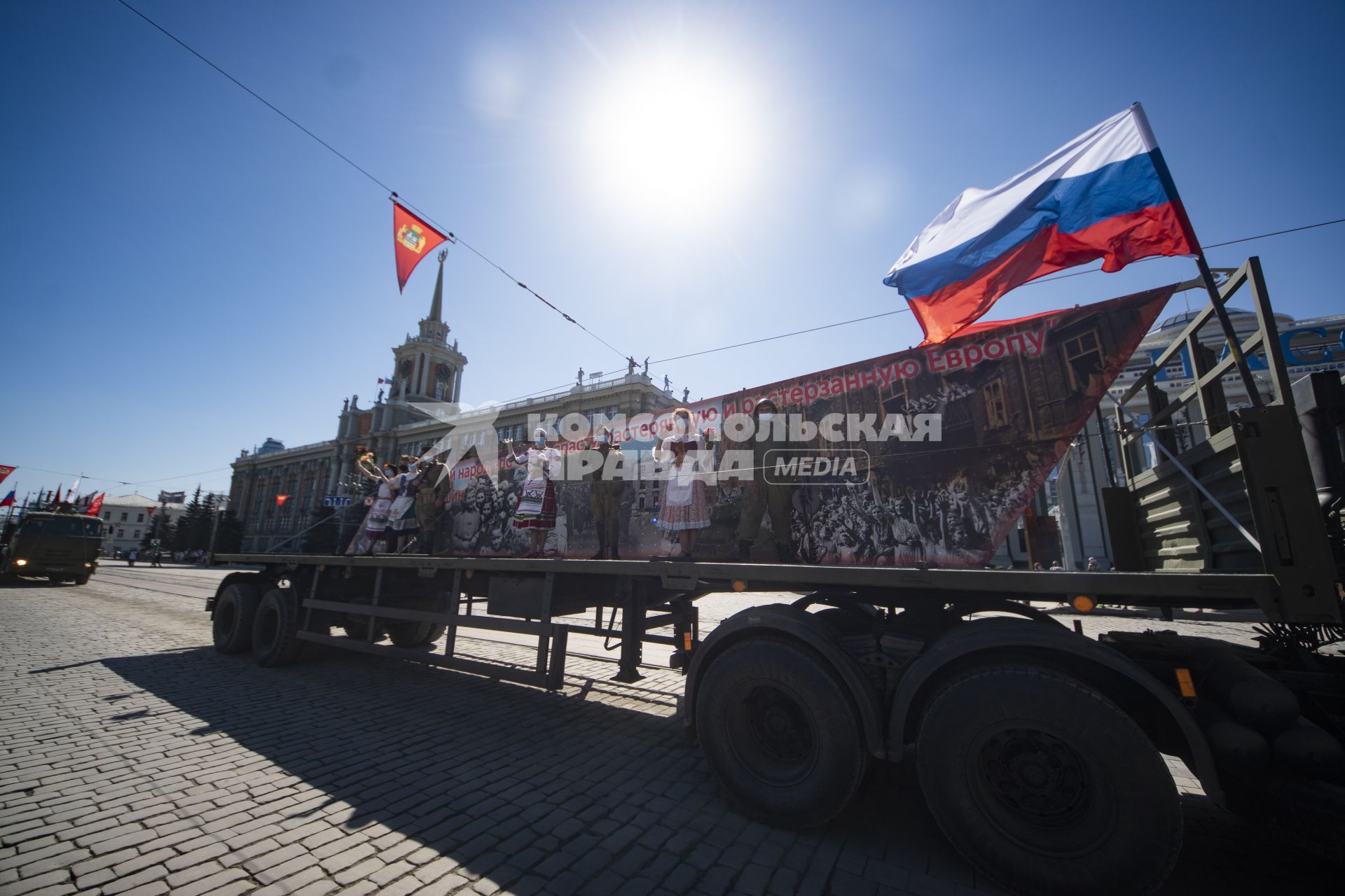 Екатеринбург. Горожане наблюдают за прохождением колонны военных грузовиков с платформами-баннерами с изображением основных этапов Великой Отечественной войны, на проспекте Ленина во время праздничных мероприятий в честь 75-й годовщины победы в ВОВ, во время режима самоизоляции введеного для нераспространения новой коронавирусной инфекции COVID-19