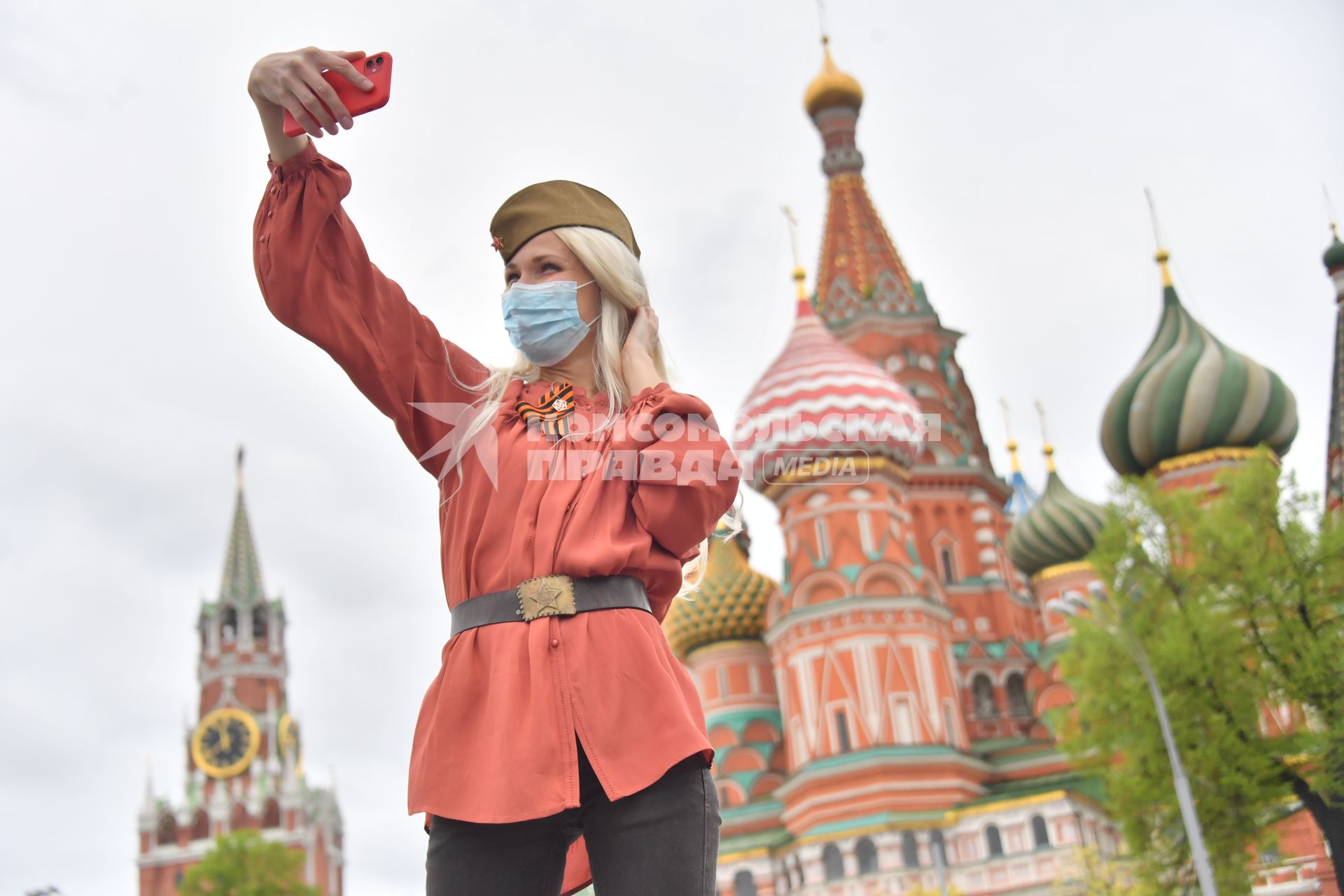 Москва.  Девушка в медицинской маске делает селфи на Красной площади во время празднования Дня Победы.