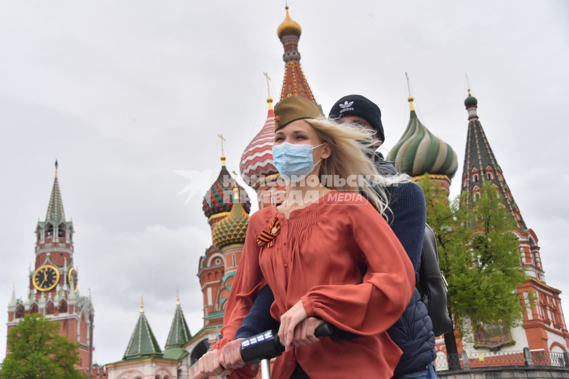 Москва.  Молодые люди в медицинских масках на Красной площади во время празднования Дня Победы.