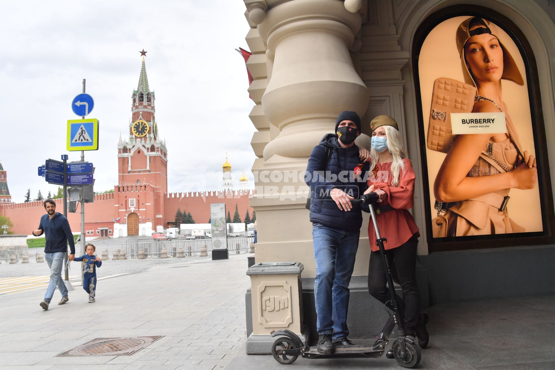 Москва.  Молодые люди в медицинских масках на Красной площади во время празднования Дня Победы.