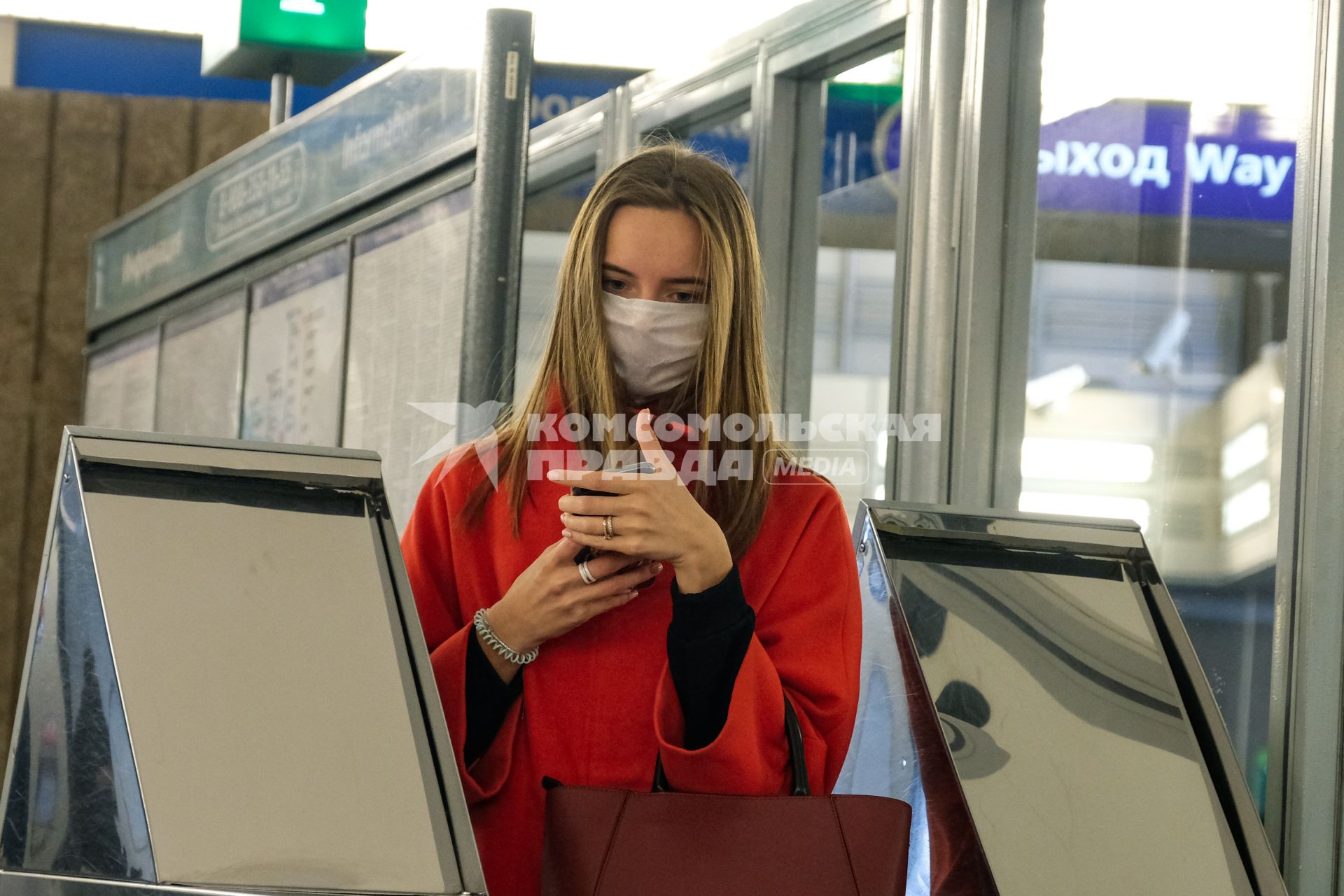 Санкт-Петербург.  Женщина в медицинской маске проходит через турникет.